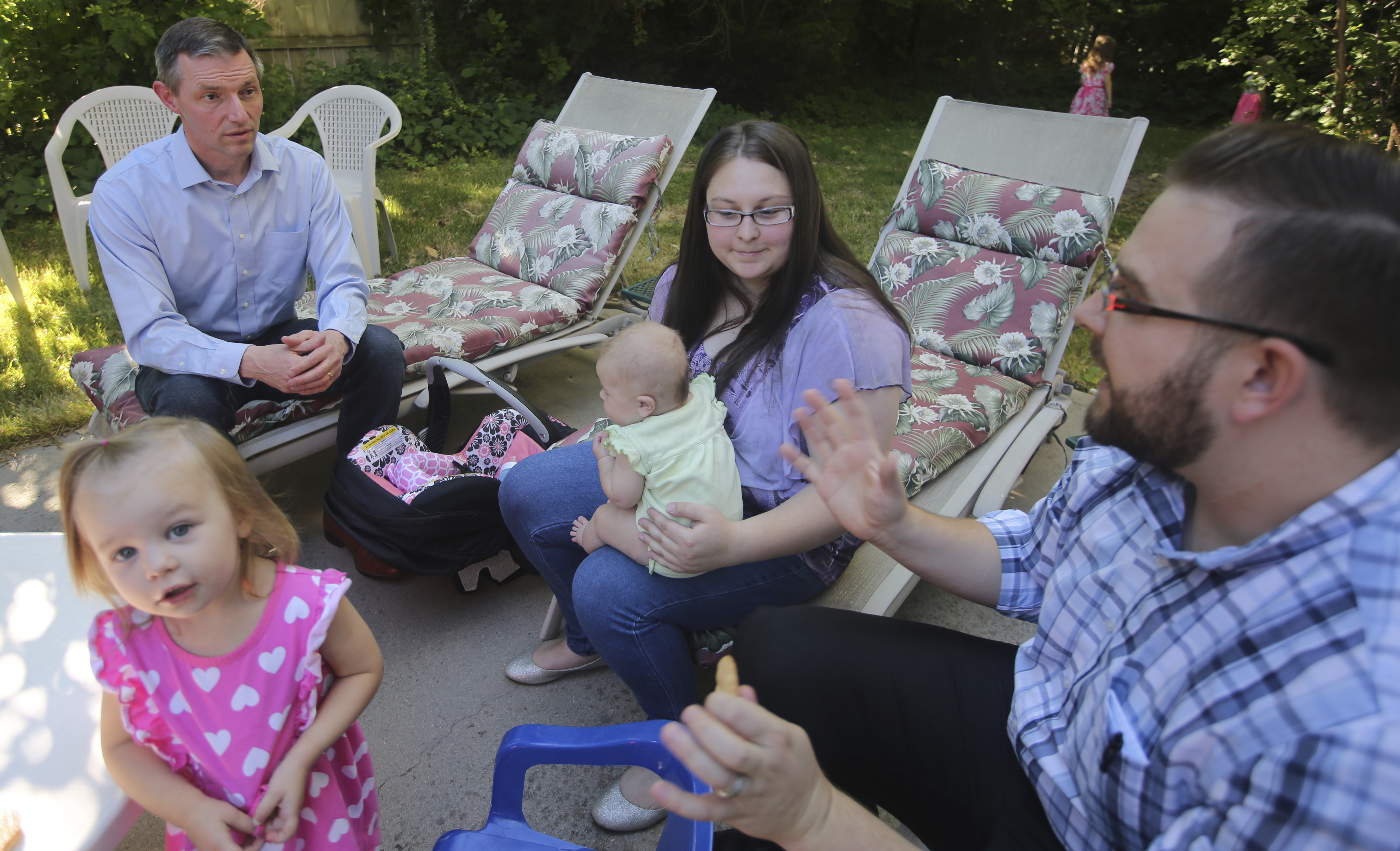 In this Friday, June 22, 2018, photo, Mike Kennedy, left, speaks with a family at a backyard meet and greet in Holladay, Utah. Mitt Romney faces state lawmaker Kennedy on Tuesday, June 26, 2018, as the ex-presidential nominee looks to restart his political career with the Utah's open U.S. Senate seat. Romney is competing with Kennedy in a primary election to replace U.S. Sen. Orrin Hatch, who is retiring after more than 40 years in office. (AP Photo/Rick Bowmer)