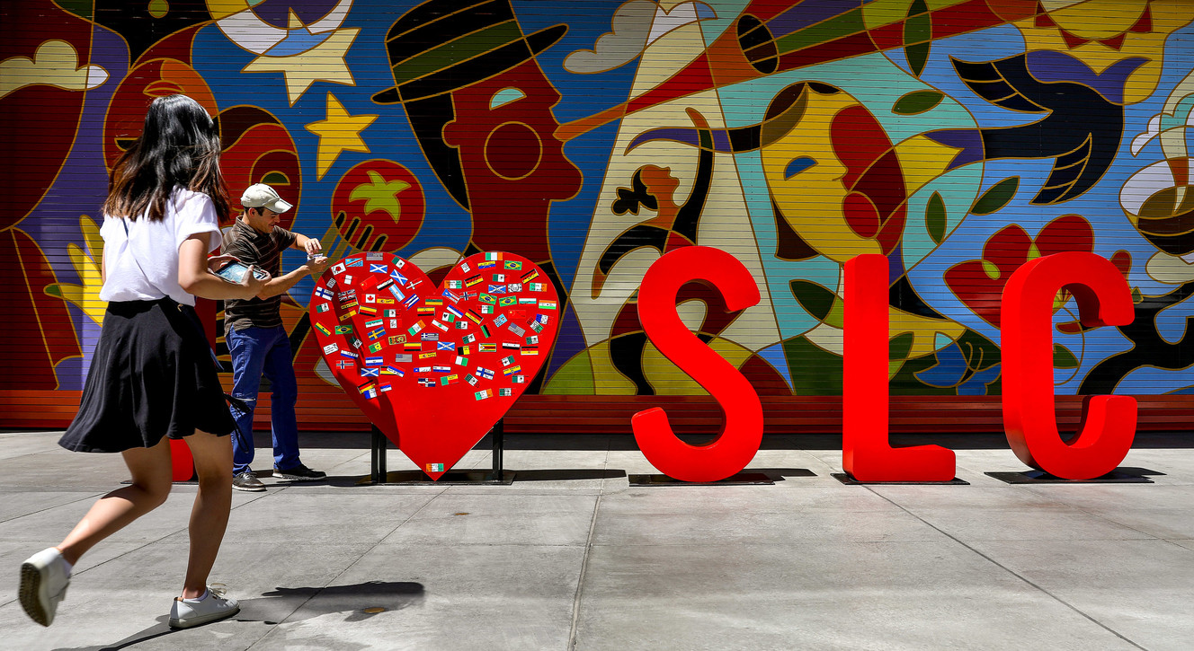 A man places a sticker on a metal heart, part of an interactive public art installation, outside the Eccles Theater in Salt Lake City on Tuesday, June 26, 2018. The art installation, which is part of Immigrant Heritage Month, features metal letters that spell out "I ‘heart’ SLC.” On Tuesday, people were encouraged to share their immigrant identity on the art itself by placing a flag of their identified heritage on the heart. Photo: Steve Griffin, KSL