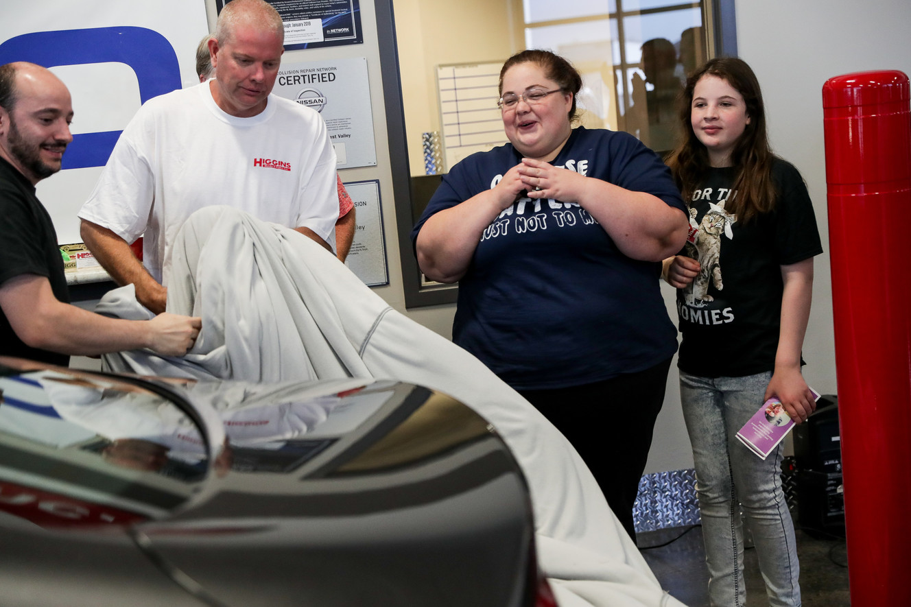 Darlene Lefevre and her daughter, Sophia, 10, watch as the cover is pulled off a 2015 Chrysler 200 that was donated to them at Higgins Body and Paint in West Valley City on Wednesday, June 27, 2018. Geico and Higgins Body and Paint, along with other organizations, teamed up to donate a refurbished car to Lefevre and her daughter, who just moved out of a shelter and into an apartment a week ago. (Photo: Spenser Heaps, KSL)