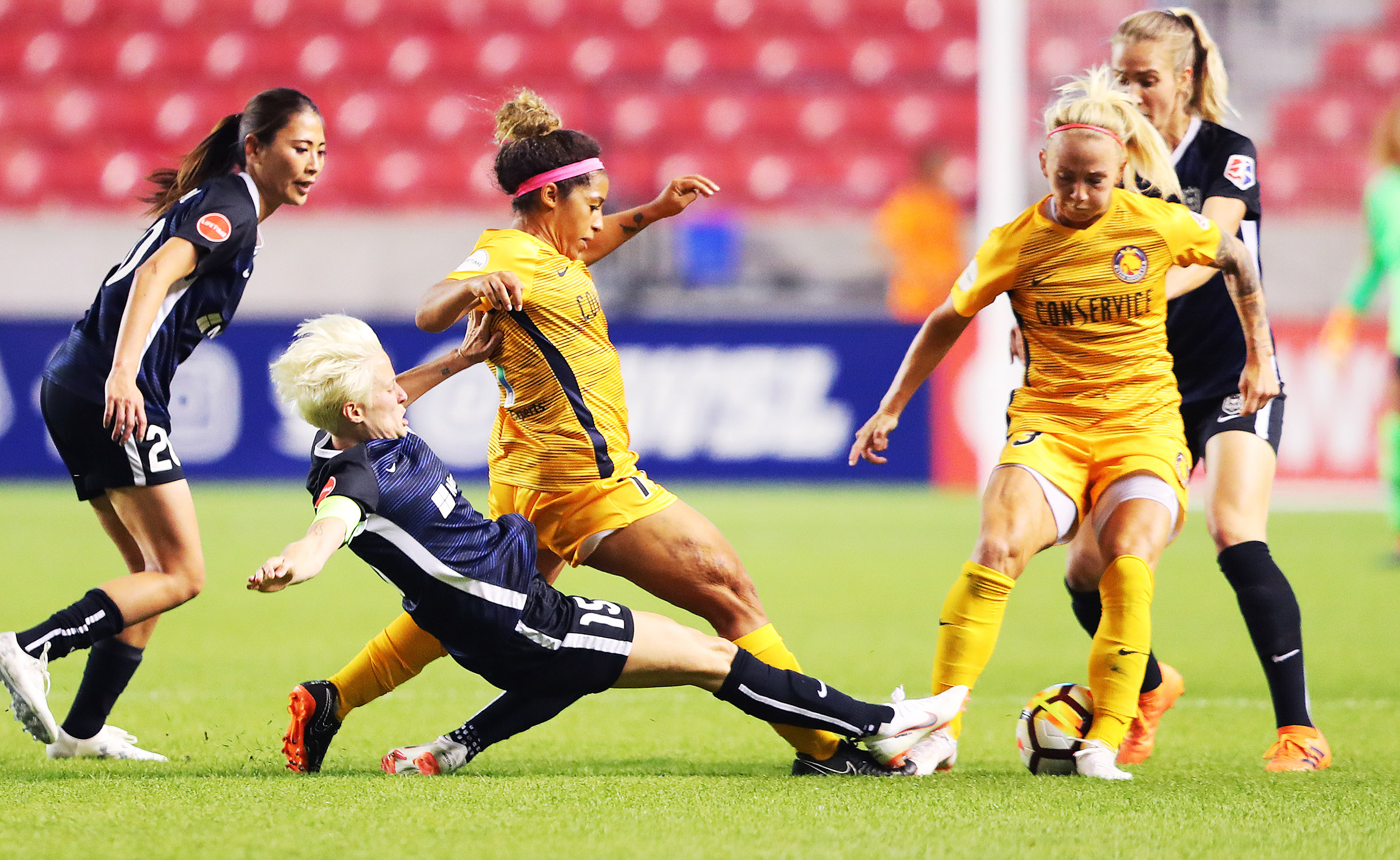 Seattle Reign FC forward Megan Rapinoe (15) slides into Utah Royals FC midfielder Desiree Scott (11) and Utah Royals FC midfielder Gunnhildur Jónsdóttir (23) as the Utah Royals and the Seattle Reign play at Rio Tinto Stadium in Sandy on Wednesday, June 27, 2018. (Photo: Scott G Winterton, Deseret News)