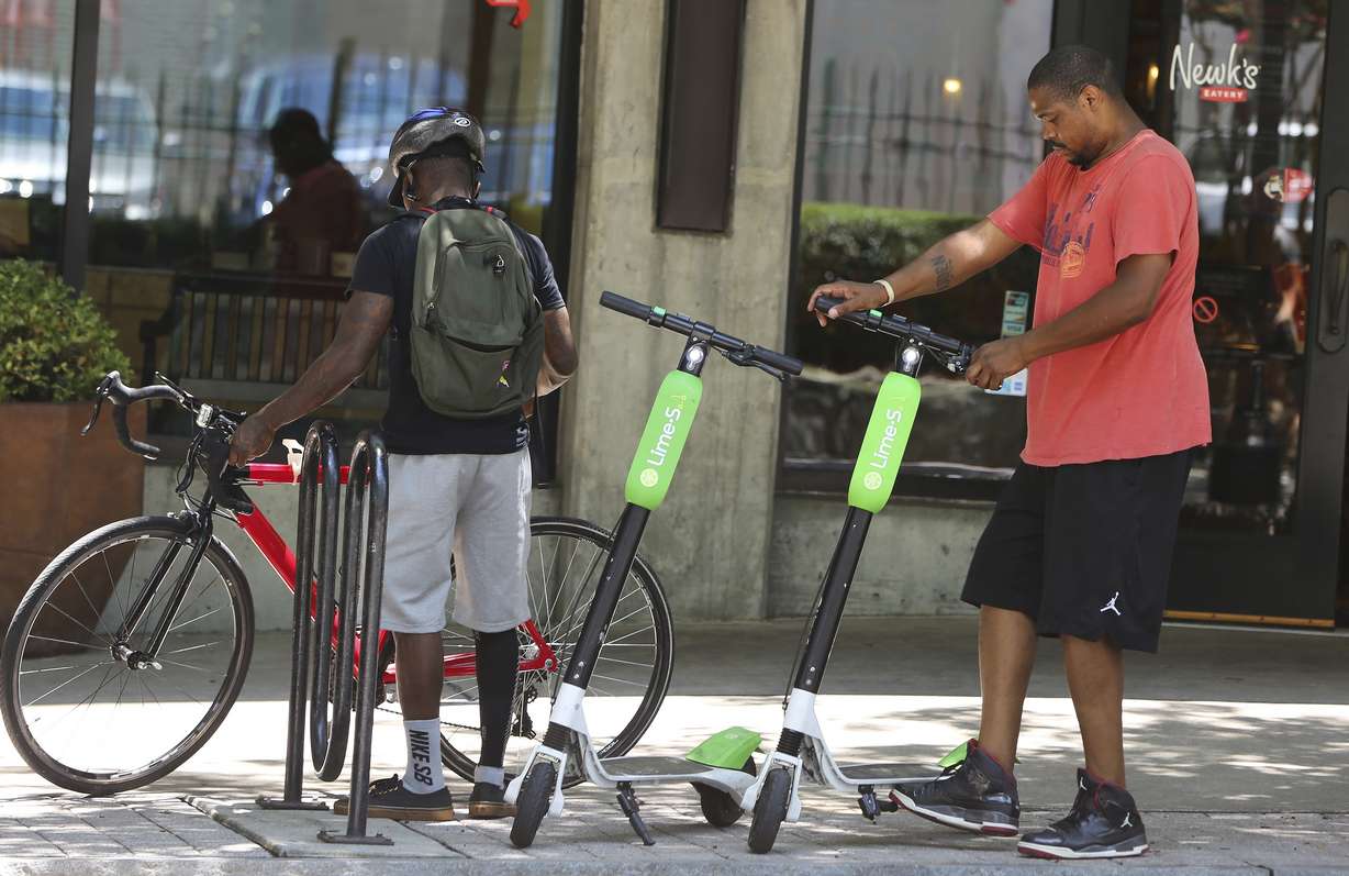FILE - In this Tuesday, June 26, 2018 photo, a man parks his rented dockless scooter outside of a restaurant in Atlanta. Cities across the U.S. are grappling with how to deal with electric scooters that have begun appearing in sidewalks overnight without any regulations. Lawsuits and cease-and-desist orders have quickly followed the arrival of California-based companies, Bird Rides Inc., LimeBike and Spin. Milwaukee will ask a judge Friday, July 12, 2018, to order Bird to remove their scooters.(AP Photo/Brinley Hineman, File)