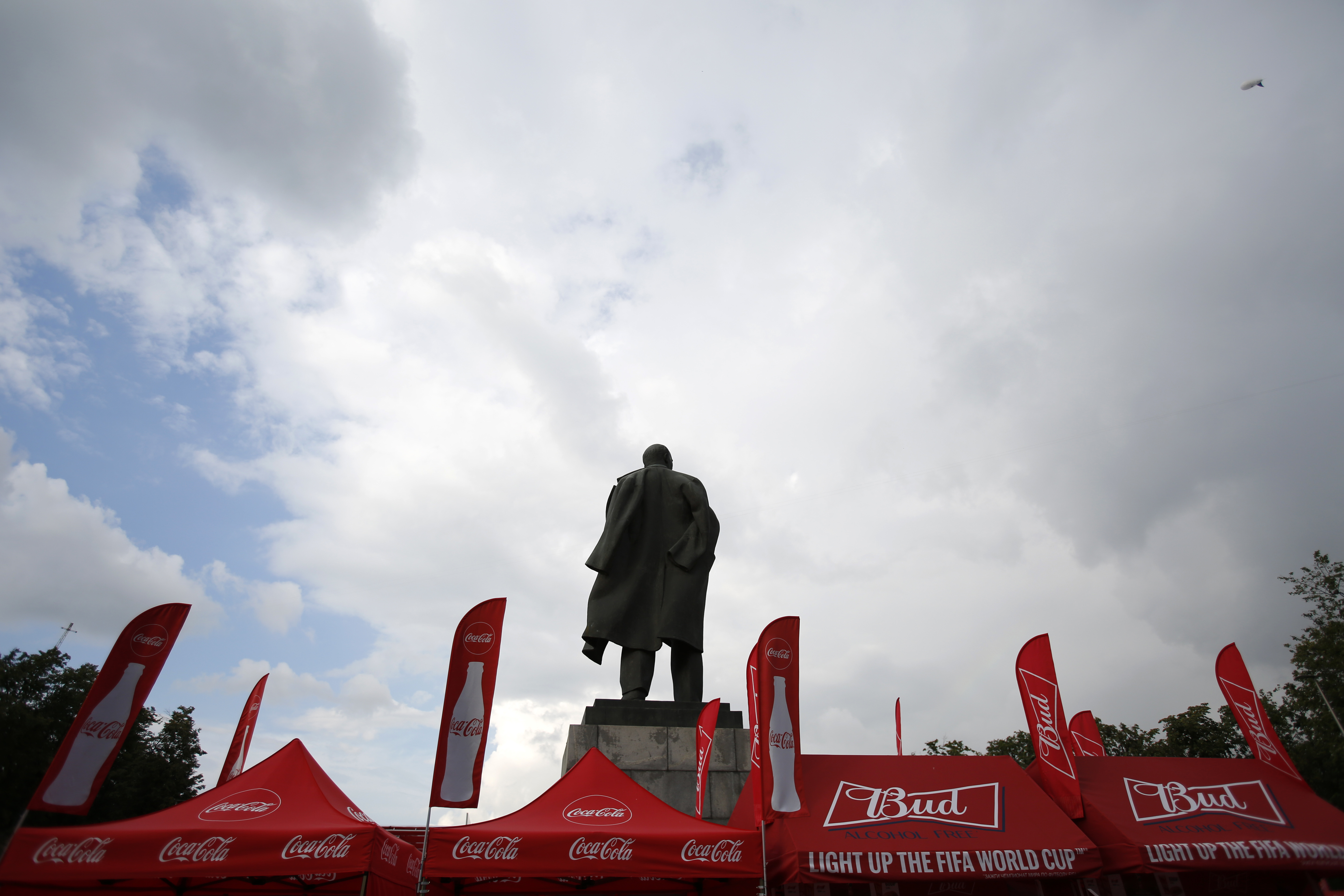 Lenin statue at final sandwiched by ads for Budweiser, Visa