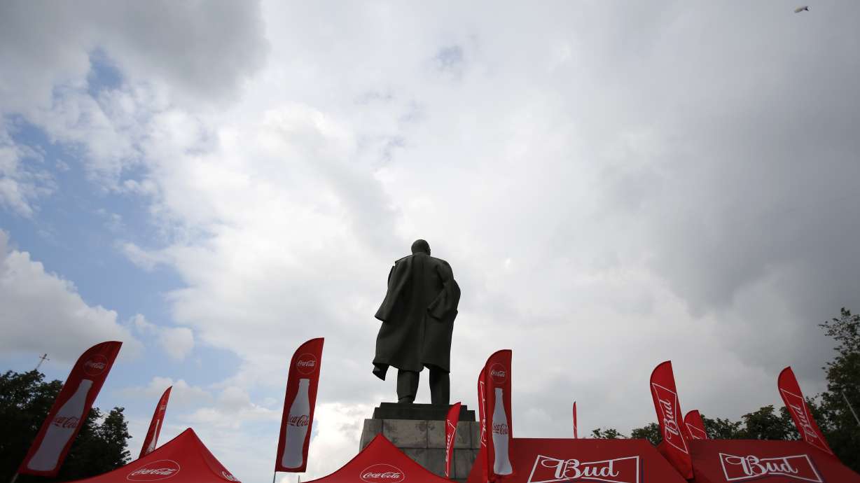 Lenin statue at final sandwiched by ads for Budweiser, Visa