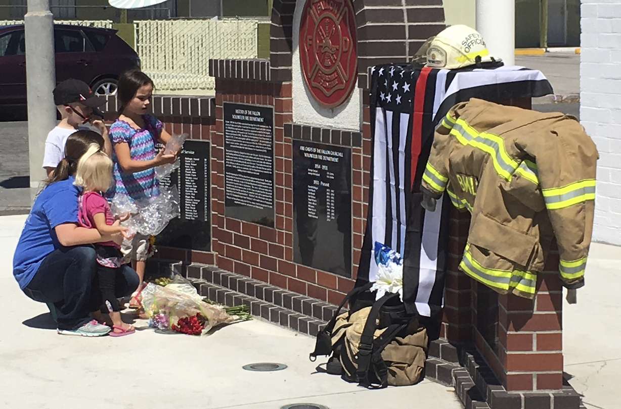 A woman who would only identify herself as a niece of shooting victim Charles 'Bert' Miller, is joined by her children as she places flowers at a makeshift memorial Monday, July 23, 2018, in Fallon, Nev., outside the fire department where Miller was a longtime volunteer firefighter. Police in the northern Nevada city are trying to determine why a 48-year-old man walked into his Mormon church on Sunday, July 22, 2018, and opened fire, killing Miller and injuring another person. (Scott Sonner, AP Photo)