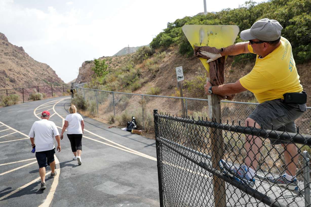 Domingo Garcia cleans up a graffitied sign on Parleys Trail in Millcreek on Saturday, July 28, 2018. Members of the Canyon Rim neighborhood of Millcreek gathered for three days of service projects. (Photo: Spenser Heaps, KSL)