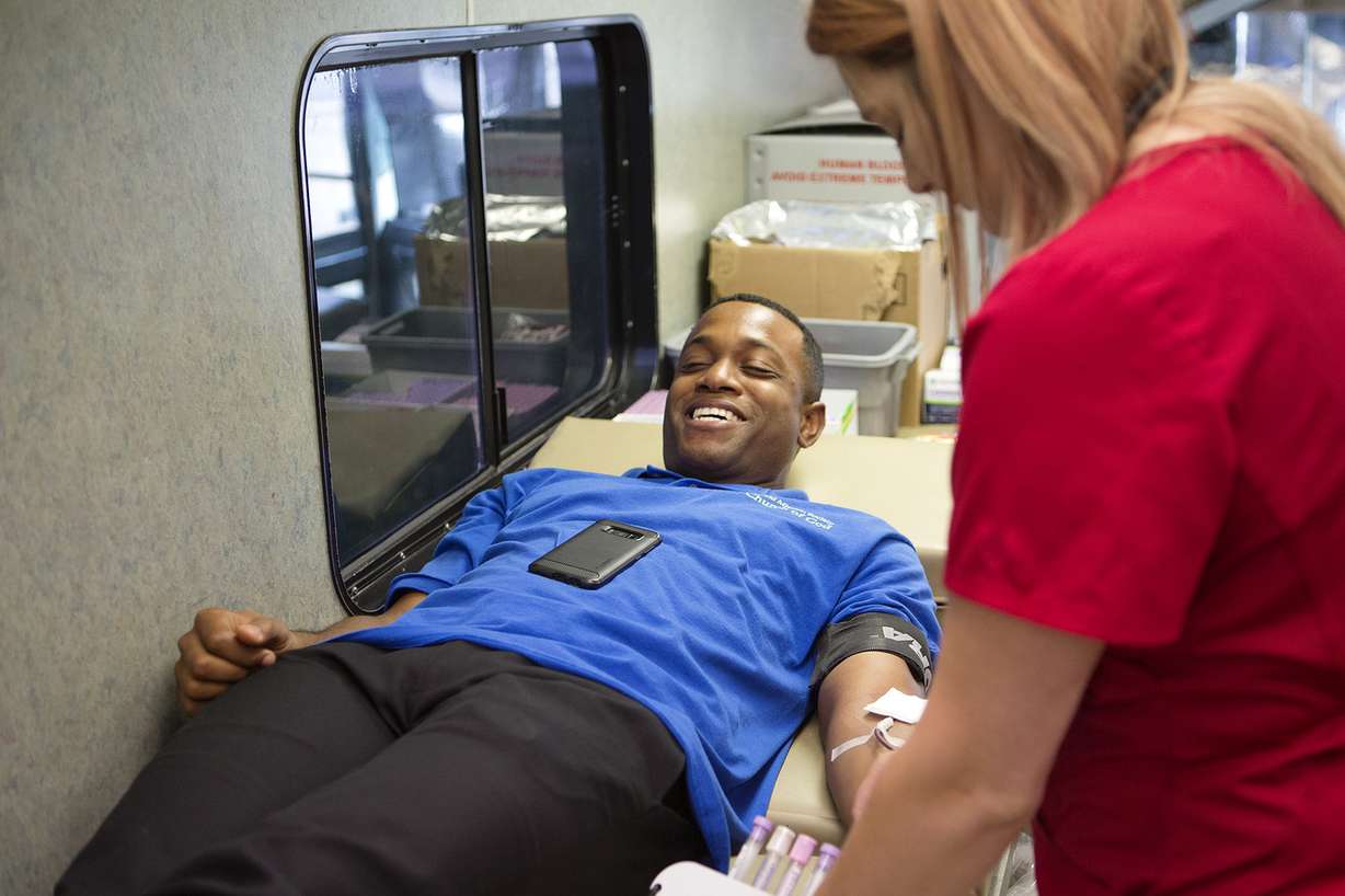 Lewis Todd chuckles as Sage Tolotti helps him give blood in an American Red Cross bus in the parking lot of the World Mission Society Church of God in Salt Lake City on Sunday, Aug. 5, 2018. (Photo: James Wooldridge, KSL)