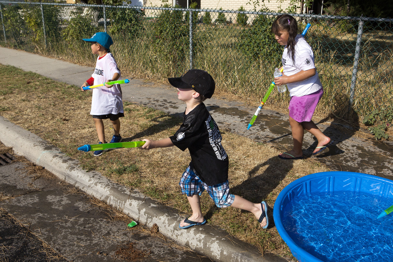 Parker Tavares, 6, center, and others take water from a kiddie pool during a water parade put on by the Jordan Meadows Community Council, Westpointe Community Council and the Salt Lake City Police Department as part of the "Night Out Against Crime" in Salt Lake City on Tuesday, Aug. 7, 2018. (Photo: James Wooldridge, KSL)