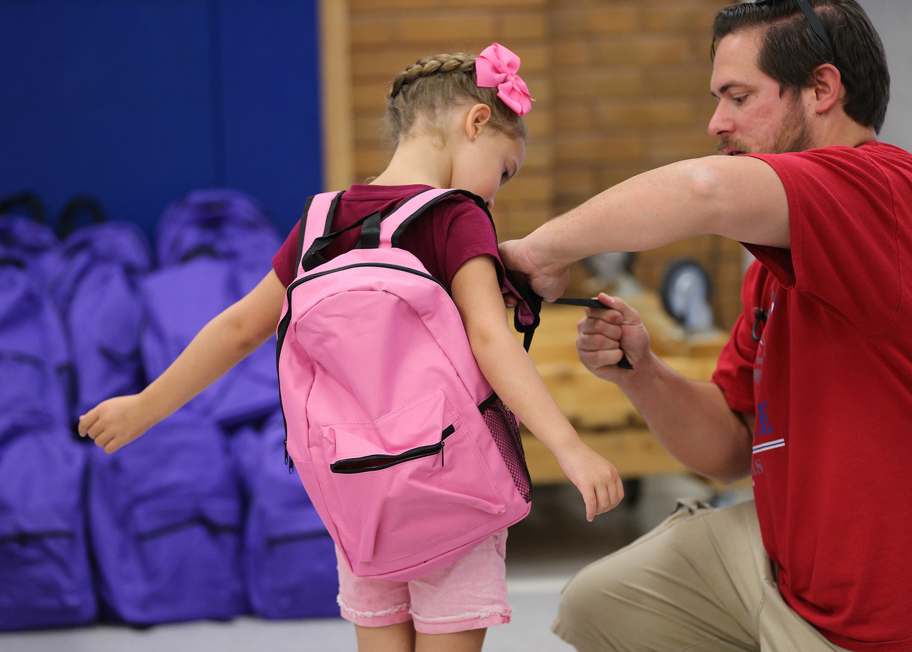 Olivia Papciak gets some help with her new backpack from her father, Chris, at Hill Field Elementary School in Clearfield on Friday, Aug. 10, 2018. The giveaway was organized by national nonprofit Operation Homefront, which provides several services to the families of military members and anticipates giving away 22,000 backpacks to children across the United States for the new school year. (Photo: Jeffrey D. Allred, KSL)