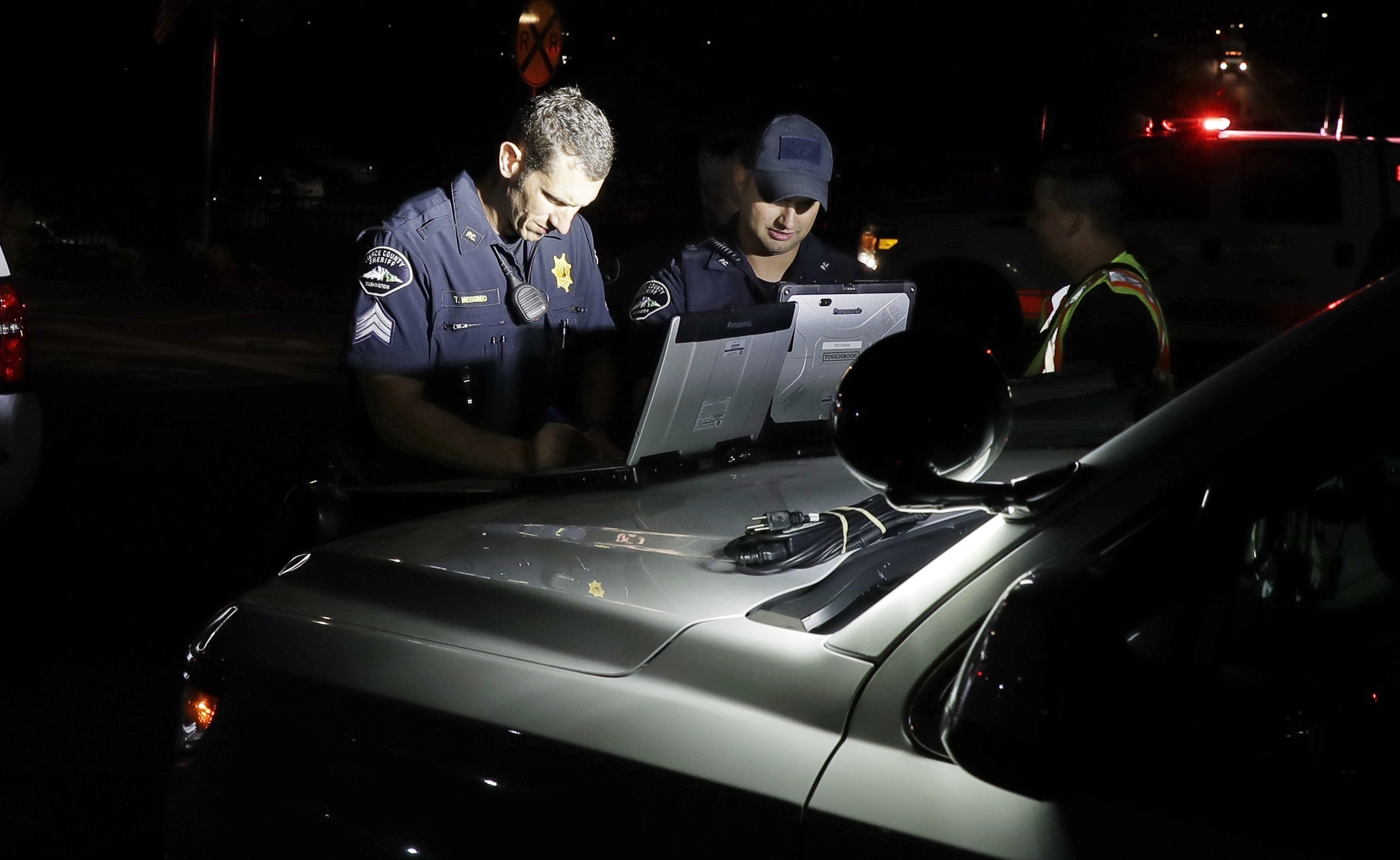 Law enforcement officials work at a staging area, Friday, Aug. 10, 2018, at the ferry terminal in Steilacoom, Wash., near where a Coast Guard spokeswoman said the agency was responding to a report of a smoke plume and possible plane crash. Earlier in the evening, officials at Seattle-Tacoma International Airport said an Alaska Airlines plane had been stolen and later crashed. (AP Photo/Ted S. Warren)