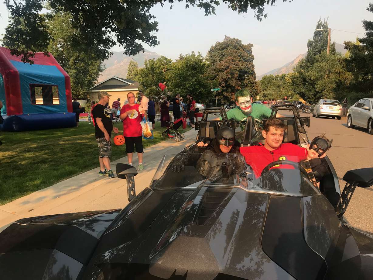 Corbin Thorpe (right) rides a makeshift Batmobile with his brother, Taylor Thorpe (middle) down a Millcreek street on Friday, Aug. 10, 2018. A community in Millcreek organized an early Halloween celebration for Corbin who is terminally ill and may not live to Oct. 31 this year, according to his doctors.