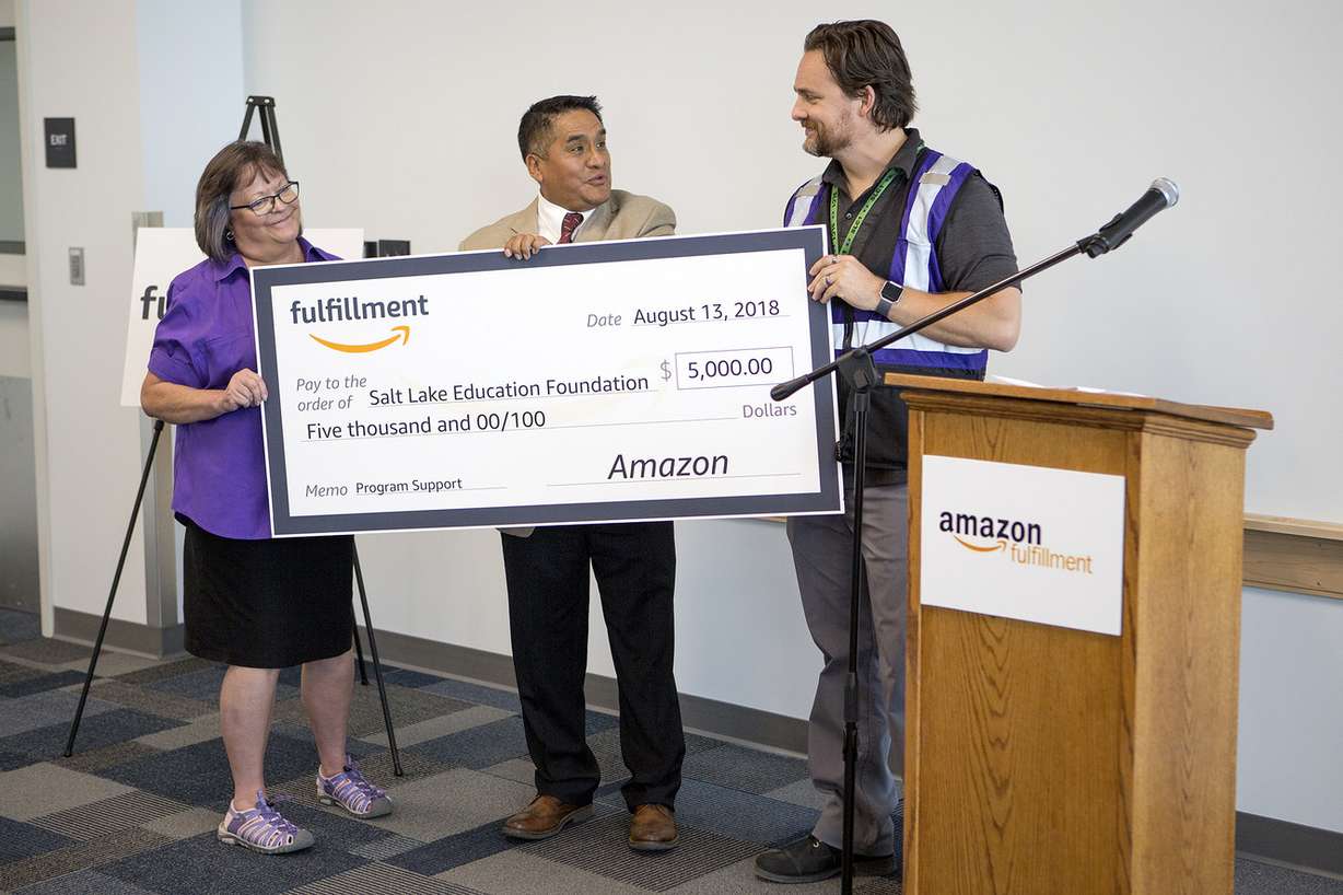 Michael Taylor, right, general manager of Amazon's new Utah fulfillment center, presents a check to the Salt Lake Education Foundation's James Yapias and Cynthia Holz at the new facility in Salt Lake City on Monday, Aug. 13, 2018. (Photo: James Wooldridge, KSL)