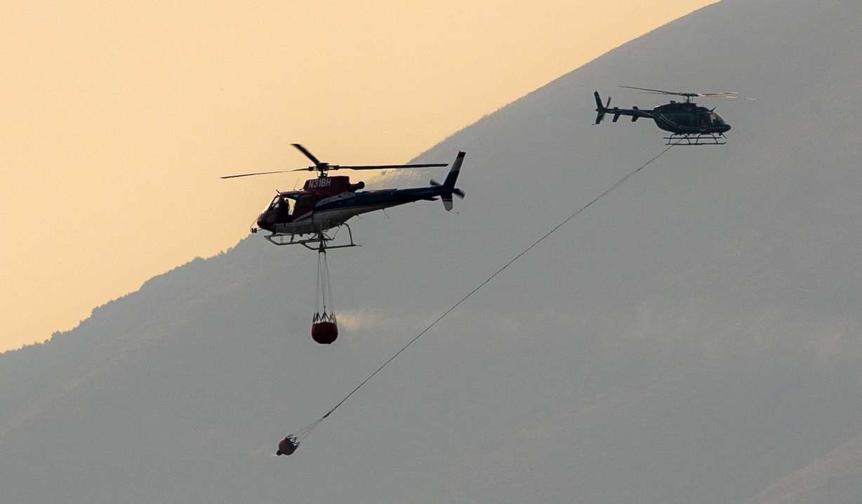 Helicopters pass each other as they work a fire burning above Herriman on Saturday, Aug. 18, 2018. (Photo: Scott G. Winterton, KSL)