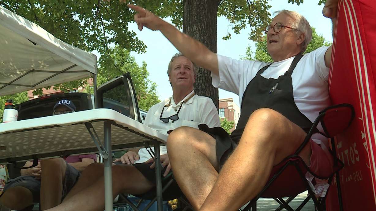 Tony Caputo offers his opinions to a woman contemplating a trip to Taiwan at his "Old Coots" booth in Salt Lake City's Pioneer Park Saturday, Aug. 18, 2018. (Photo: Ray Boone, KSL TV)