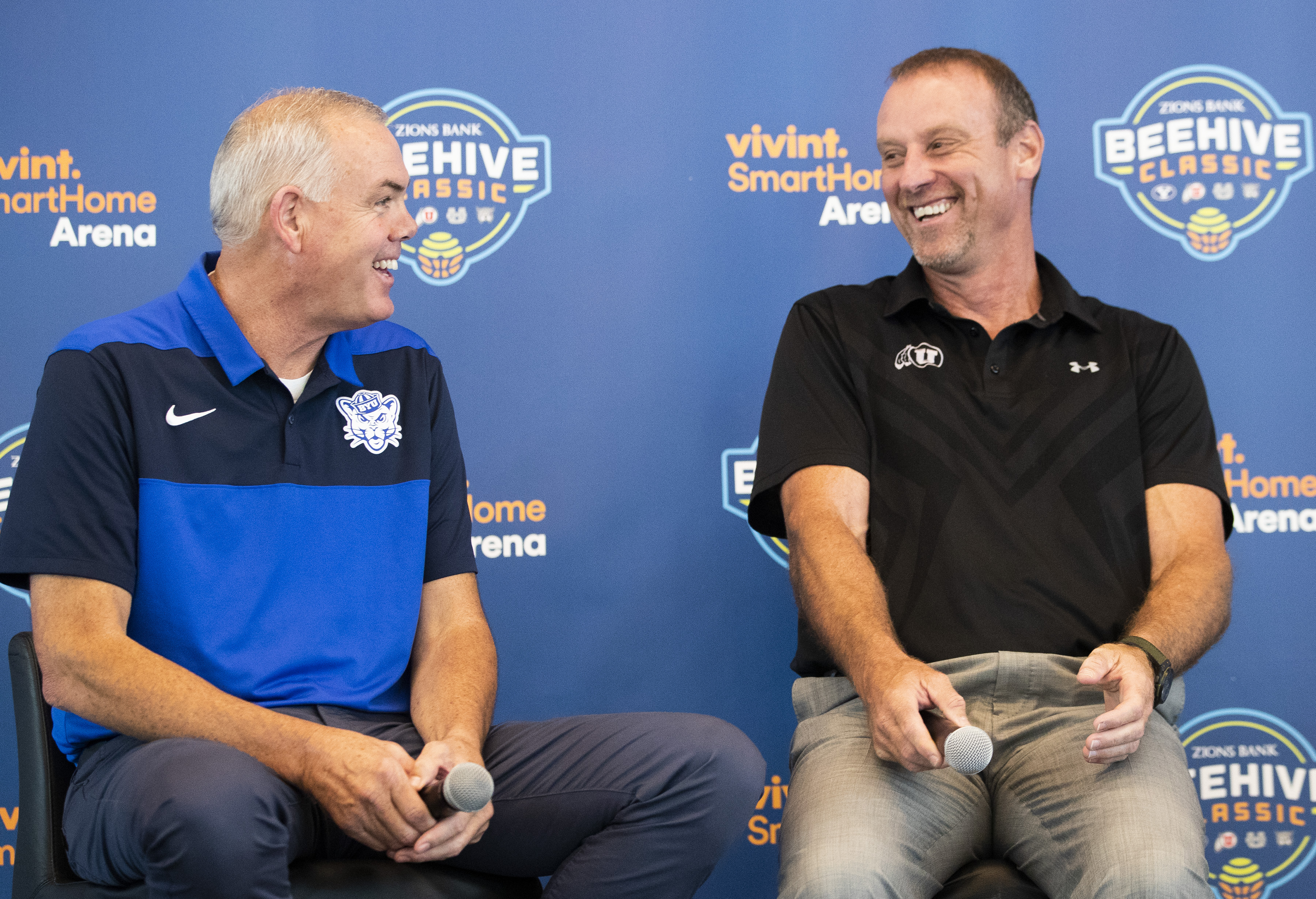 Head coaches Dave Rose, BYU, Larry Krystkowiak, Utah, share a laugh as they join other coaches Craig Smith, Utah State, and Randy Rahe, Weber State, to promote the Beehive Classic at a press conference at Vivint Smart Home Arena in Salt Lake City on Tuesday, Aug. 21, 2018. (Photo: Scott G Winterton, Deseret News)