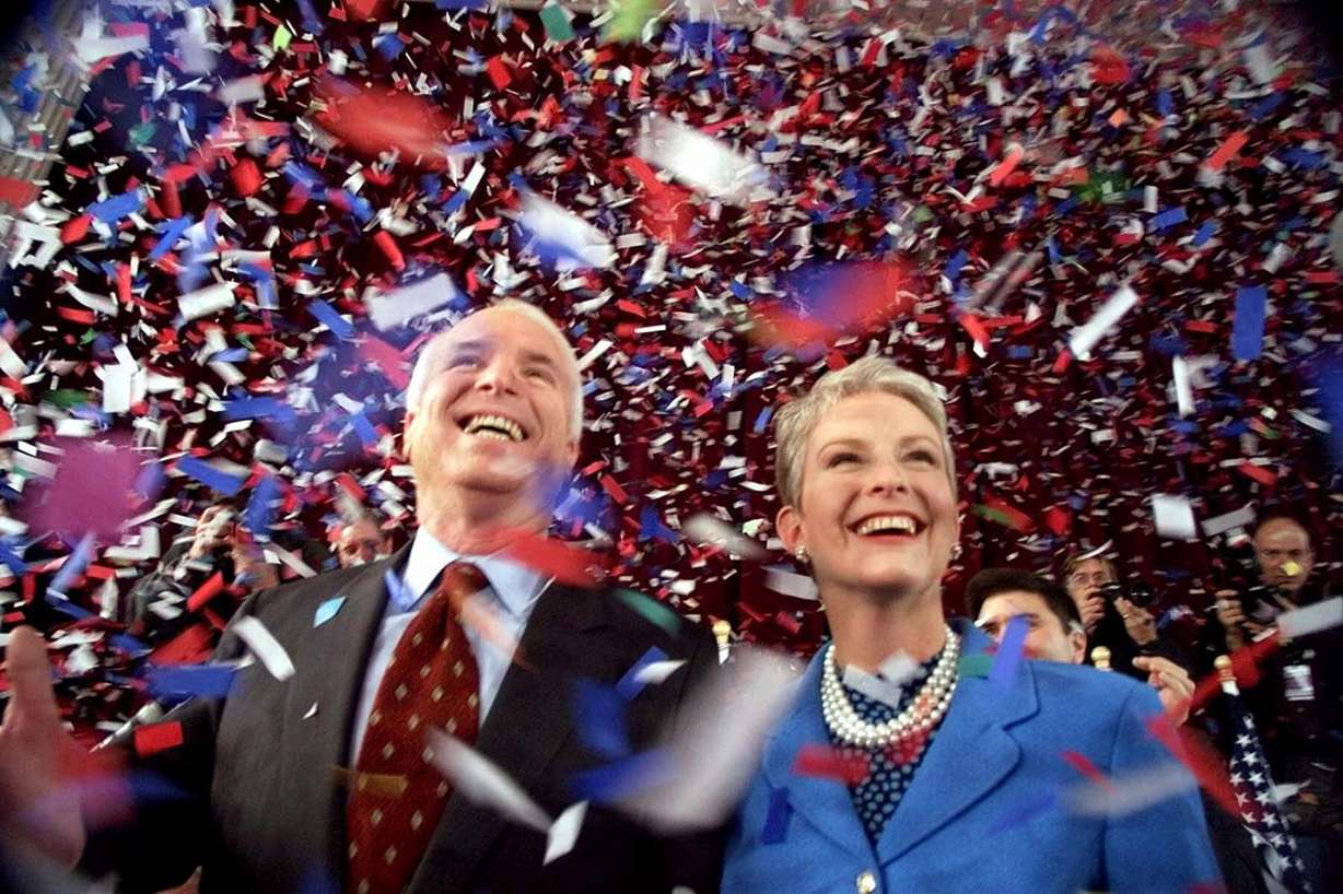 FILE - In this Jan. 30, 2000, file photo, confetti falls on Republican presidential hopeful Sen. John McCain, R-Ariz., and his wife, Cindy, at the end of their 114th New Hampshire town hall meeting with voters at the Peterborough Town House in Peterborough, N.H. Aide says senator, war hero and GOP presidential candidate McCain died Saturday, Aug. 25, 2018. He was 81. (AP Photo/Stephan Savoia, File)