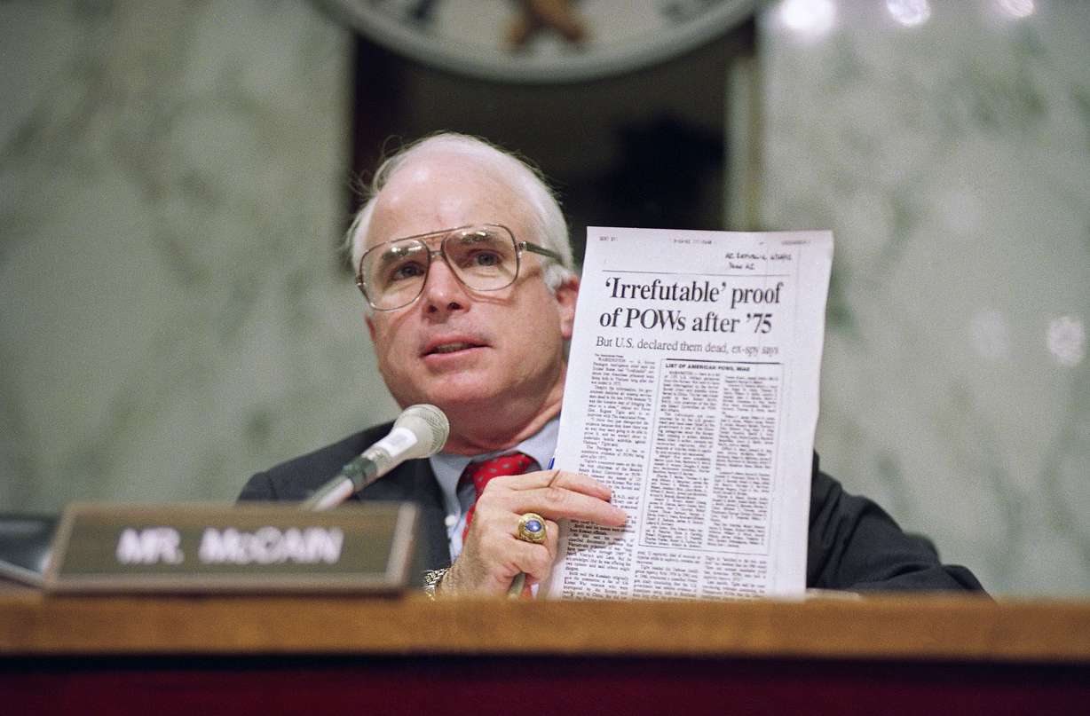 FILE - In this June 24, 1992, file photo, Sen. John McCain, R-Ariz., holds up an article from the Washington Times during a hearing of the Senate Select Committee on POW/MIA Affairs on Capitol Hill in Washington. Arizona Sen. McCain, the war hero who became the GOP's standard-bearer in the 2008 election, has died. He was 81. His office says McCain died Saturday, Aug. 25, 2018. He had battled brain cancer. (AP Photo/John Duricka, File)