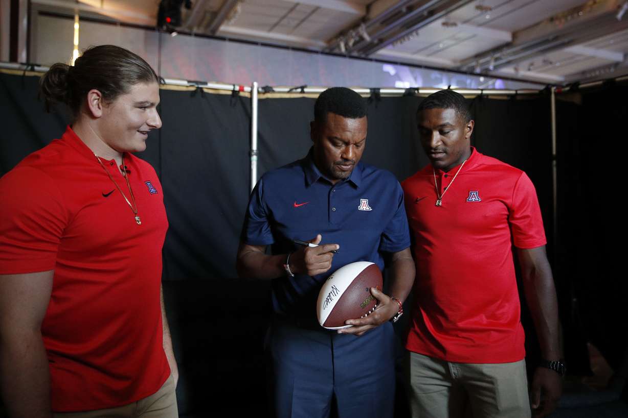Flanked by linebacker Colin Schooler, left, and quarterback Khalil Tate, Arizona coach Kevin Sumlin signs his autograph at the Pac-12 Conference NCAA college football media day in Los Angeles, Wednesday, July 25, 2018. (Photo: Jae C. Hong, AP)