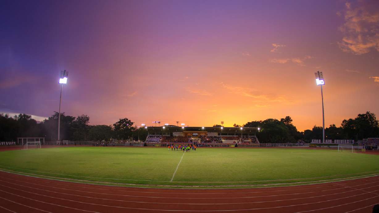 Stock image of a football field with a sunset in the background.