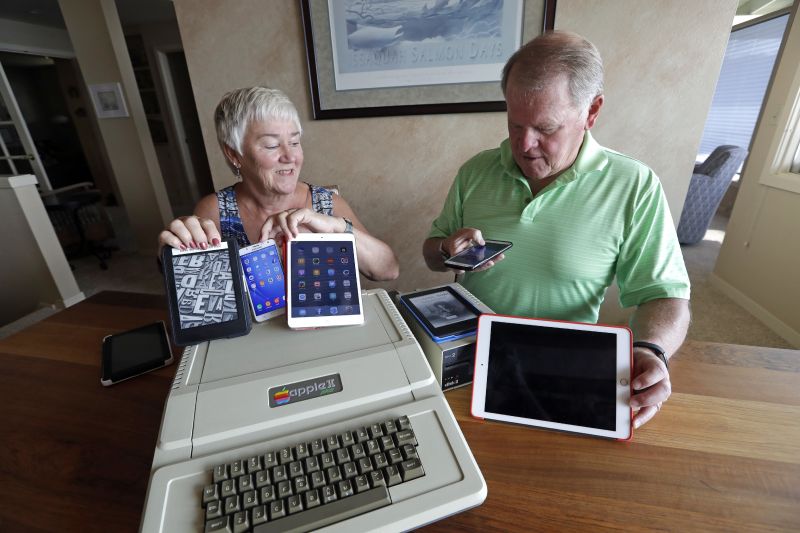 In this Wednesday, Aug. 29, 2018, photo, Kathy and Steve Dennis display several of their own cell phones and computer tablets along with their 1980's-era Apple II+ computer bought for their then young sons in Bellevue, Wash. Three decades ago they never heard the phrase "screen time," nor did they worry much about limiting the time the kids spent with technology, considering the computer an investment in their future. Things have changed with their grandkids and their phones. (AP Photo/Elaine Thompson) - Associated Press