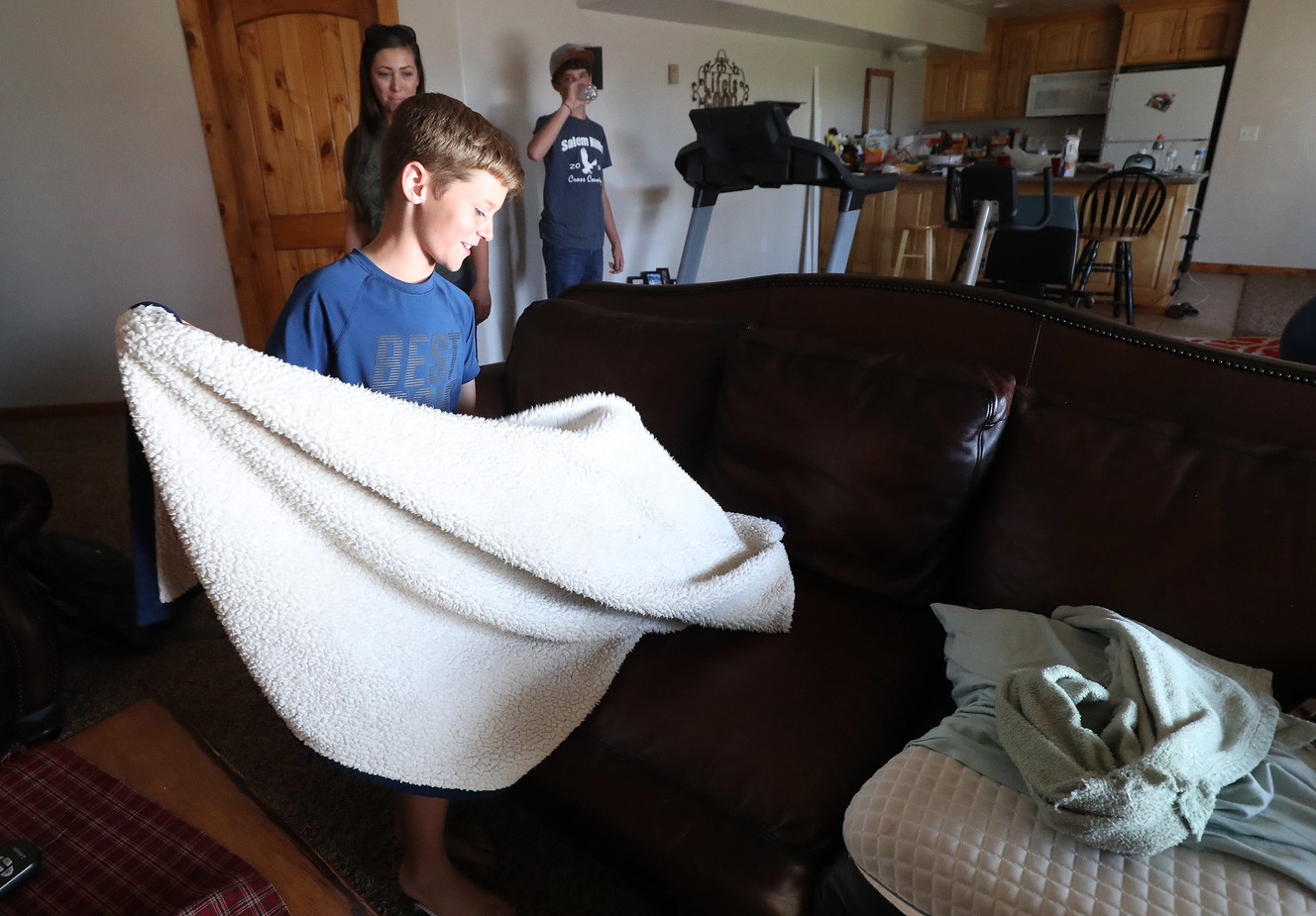 Pole Creek Fire evacuee Peyton Haskell straightens his bed on a couch as he and his family set up temporary residence at a friend's home in Salem on Thursday, Sept. 20, 2018. (Photo: Jeffrey D. Allred, KSL)