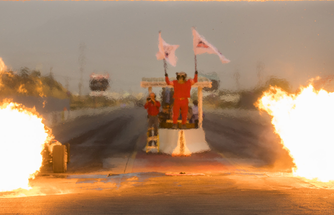 Rocky Moutain Raceways mascot Rocket holds up two flags as a pair of jet car racers test their engines before a drag race at the track on Saturday, Sept. 15, 2018. (Photo: Carter Williams, KSL.com)