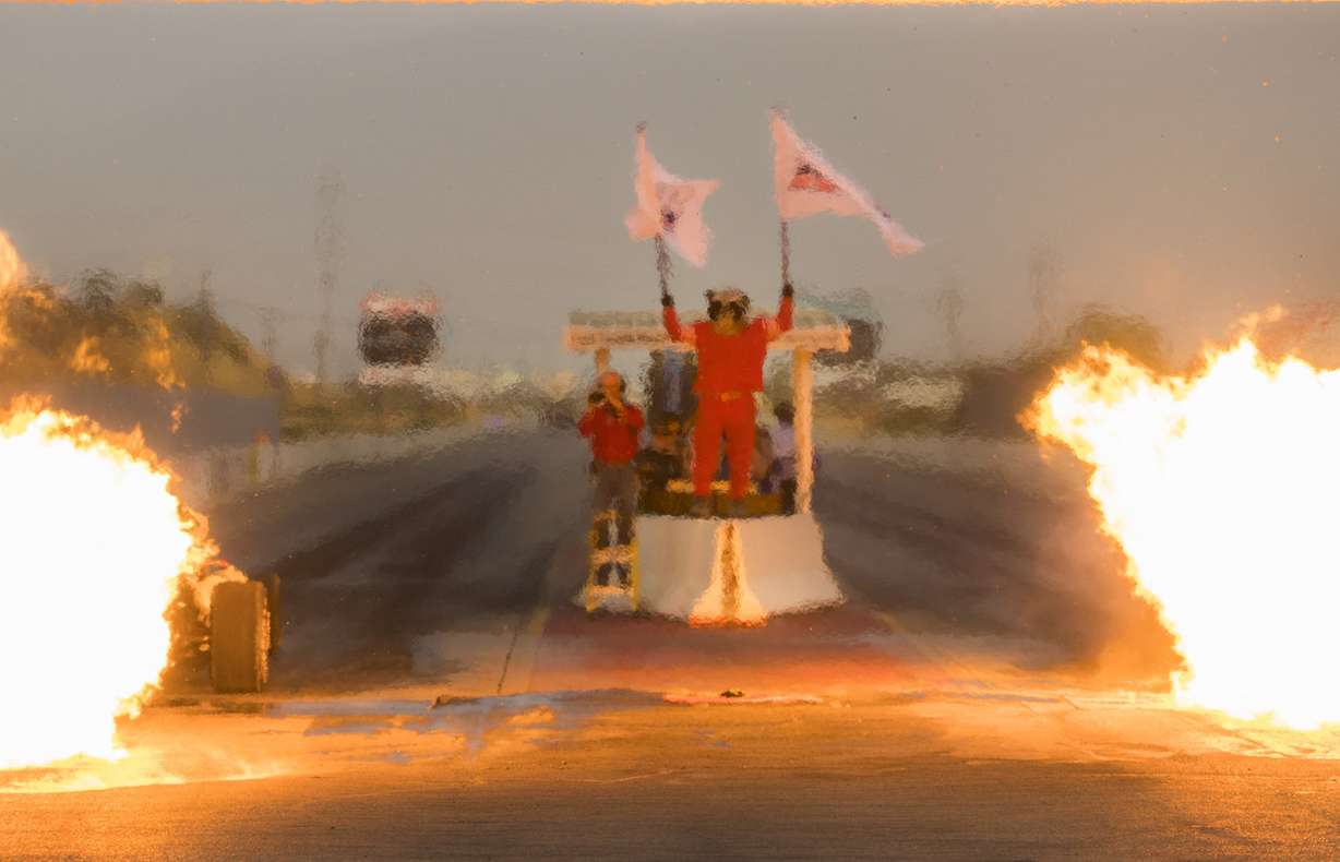 Rocky Moutain Raceways mascot Rocket holds up two flags as a pair of jet car racers test their engines before a drag race at the track on Saturday, Sept. 15, 2018. (Photo: Carter Williams, KSL.com)