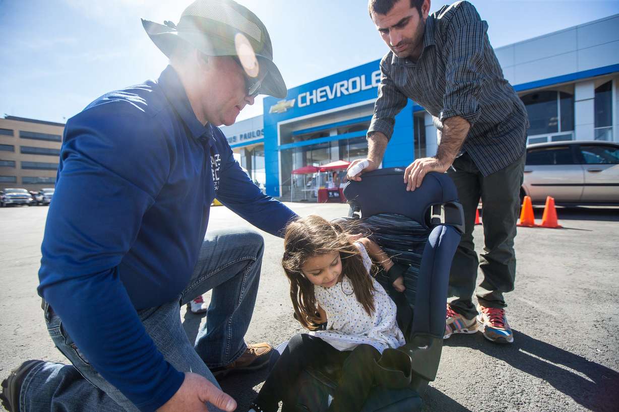Child passenger safety technician Kevin Condra, left, helps Fairda Rasuli, 4, and her father, Abudin Rasuli, adjust a car seat during a car seat checkup event at Gus Paulos Chevrolet in West Valley on Friday, Sept. 28, 2018. (Photo: Qiling Wang, Deseret News)