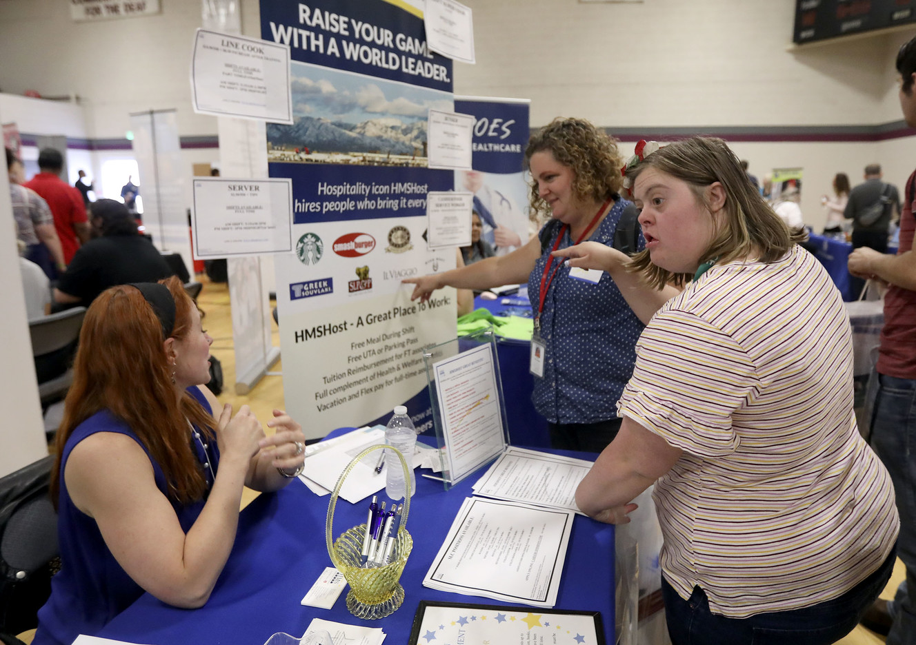 Elvira Helac, operations manager for HMS Host, and Dee Acton, human resources coordinator for HMS Host, talk to Andrew Haycock and Hallie Whetton about job opportunities during the Work Ability Job Fair, for individuals with disabilities, at the Sanderson Community Center in Taylorsville on Tuesday, Oct. 2, 2018. (Photo: Kristin Murphy, KSL)
