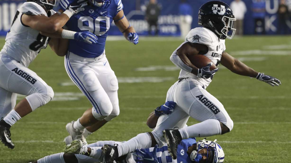Brigham Young Cougars defensive back Michael Shelton (18) makes a sliding tackle on Utah State Aggies running back Darwin Thompson (5) during the Utah State versus BYU football game at LaVell Edwards Stadium in Provo on Friday, Oct. 5, 2018.