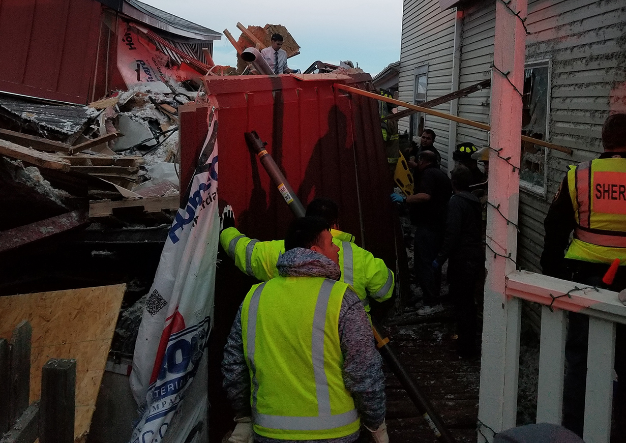 Bystanders, including Carlin Nye, and emergency crews attempt to pull two men out of a truck after it crashed into a business in Garden City on Wednesday, Oct. 10, 2018. (Photo courtesy Lance Halladay)