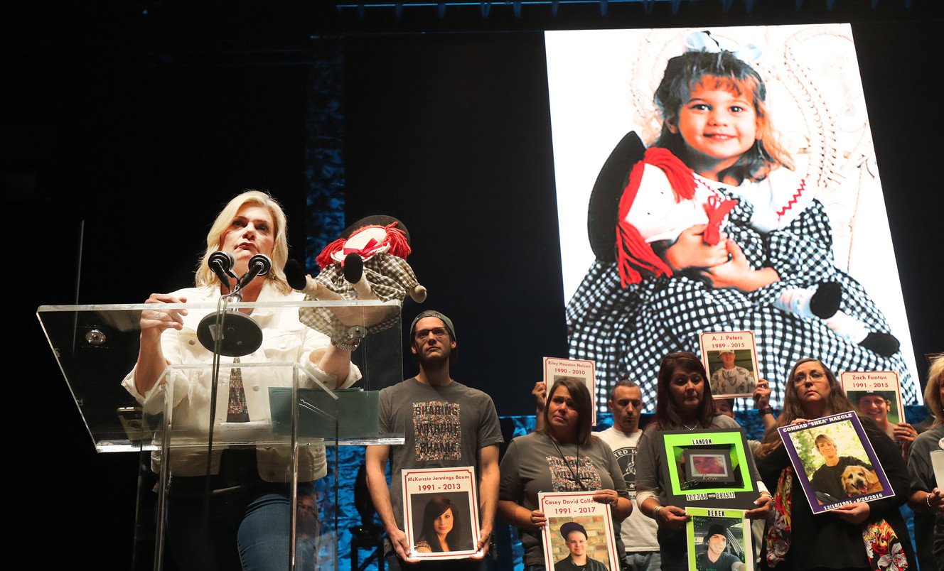 Amber Baum holds a doll her daughter, McKenzie, used to hide drugs and drug paraphernalia in during the 5th annual Utah Solution Summit in Salt Lake City on Friday, Oct. 12, 2018. McKenzie, who is pictured behind Amber Baum as a little girl holding the doll, died of an overdose. (Photo: Jeffrey D. Allred, KSL)
