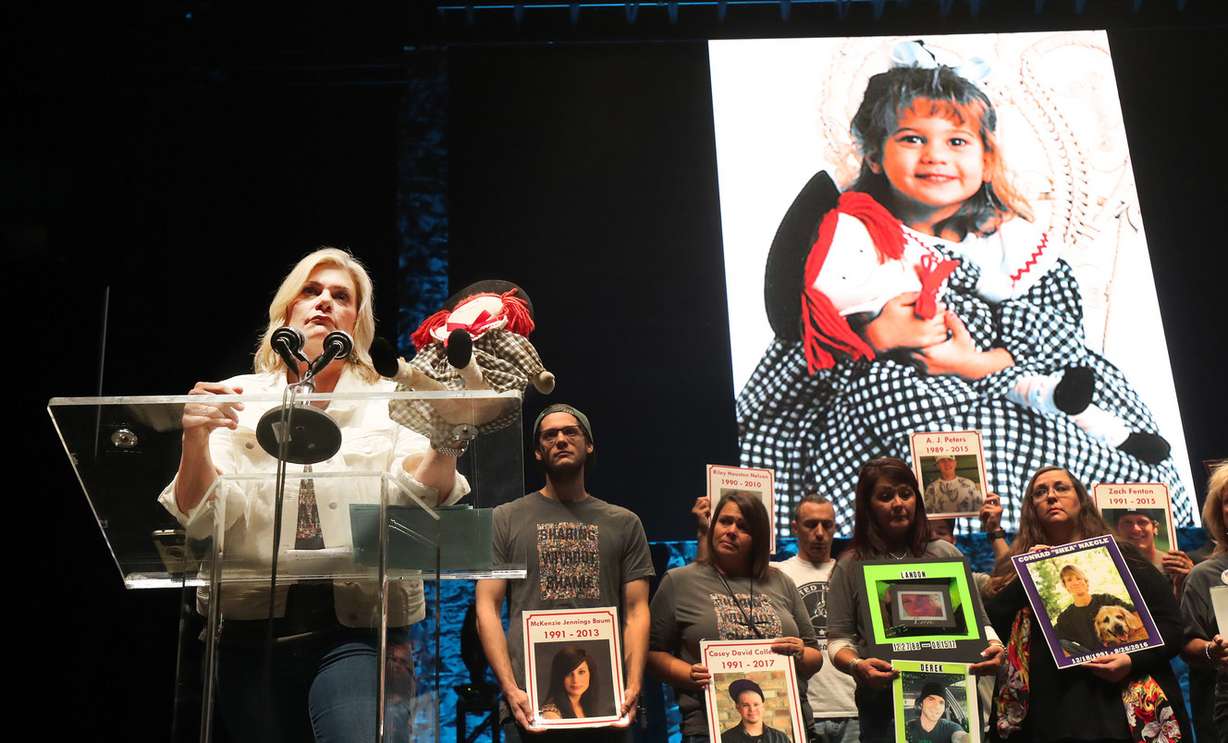 Amber Baum holds a doll her daughter, McKenzie, used to hide drugs and drug paraphernalia in during the 5th annual Utah Solution Summit in Salt Lake City on Friday, Oct. 12, 2018. McKenzie, who is pictured behind Amber Baum as a little girl holding the doll, died of an overdose. (Photo: Jeffrey D. Allred, KSL)