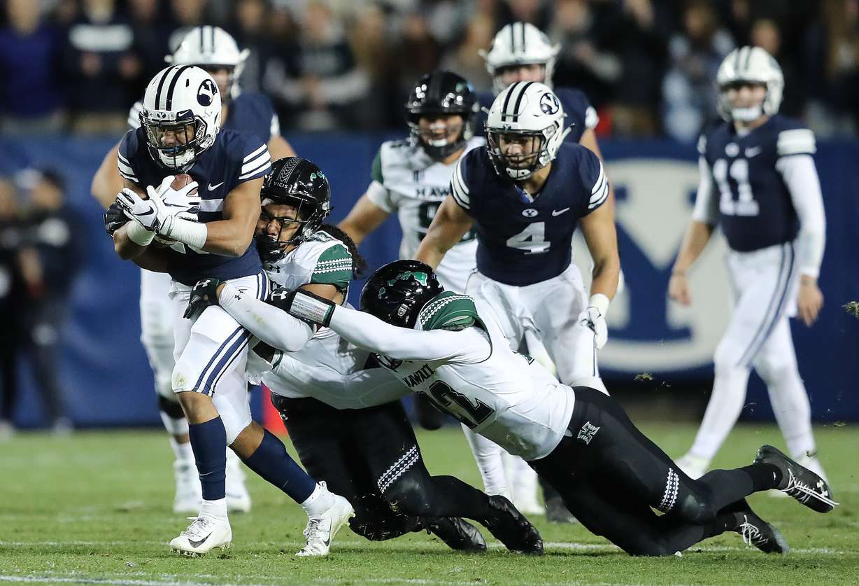 Brigham Young Cougars wide receiver Aleva Hifo (15) drags two would be tacklers Hawaii Warriors linebacker Penei Pavihi (33) and Hawaii Warriors defensive back Ikem Okeke (22) as BYU and Hawaii play at LaVell Edwards Stadium in Provo on Saturday, Oct. 13, 2018. BYU won 49-23. (Photo: Scott G Winterton, KSL)