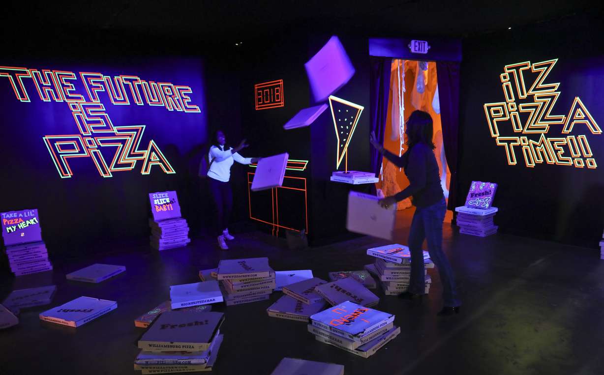 This Nov. 2, 2018 photo shows a pizza box playroom created with neon lights and colorful fluorescent tape called "Gazoo," part of a group art exhibition celebrating pizza at The Museum of Pizza in New York. (AP Photo/Bebeto Matthews)