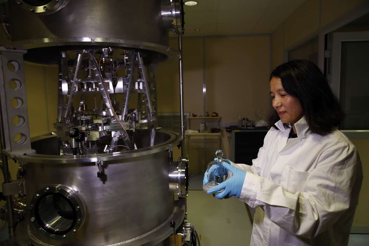In this photo taken Wednesday, Oct. 17, 2018, Executive Secretary of the Consultative Committee for Mass and related quantities (CCM) Dr Hao Fang holds a weight at the International Bureau of Weights and Measures, in Sevres, near Paris. Photo: AP Photo