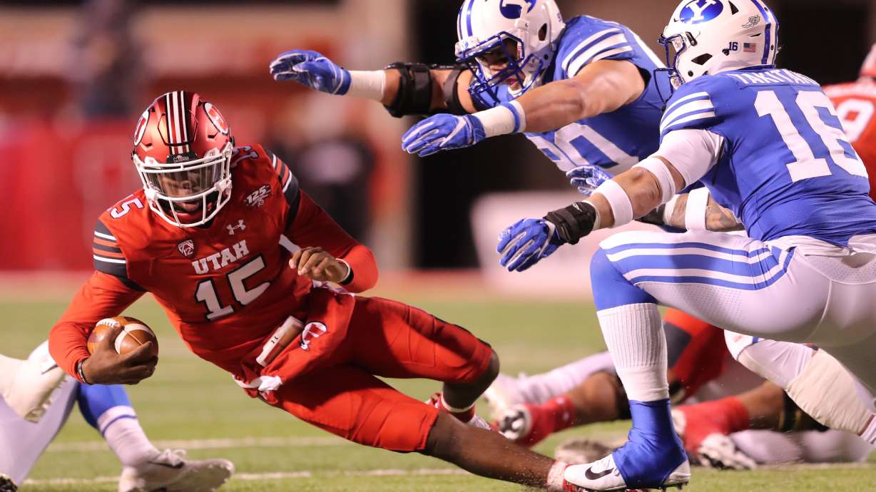 Utah Utes quarterback Jason Shelley (15) falls to the ground as Brigham Young Cougars defensive lineman Corbin Kaufusi (90) and Brigham Young Cougars linebacker Sione Takitaki (16) rush in as BYU and Utah play at Rice Eccles Stadium in Salt Lake City on Saturday, Nov. 24, 2018.