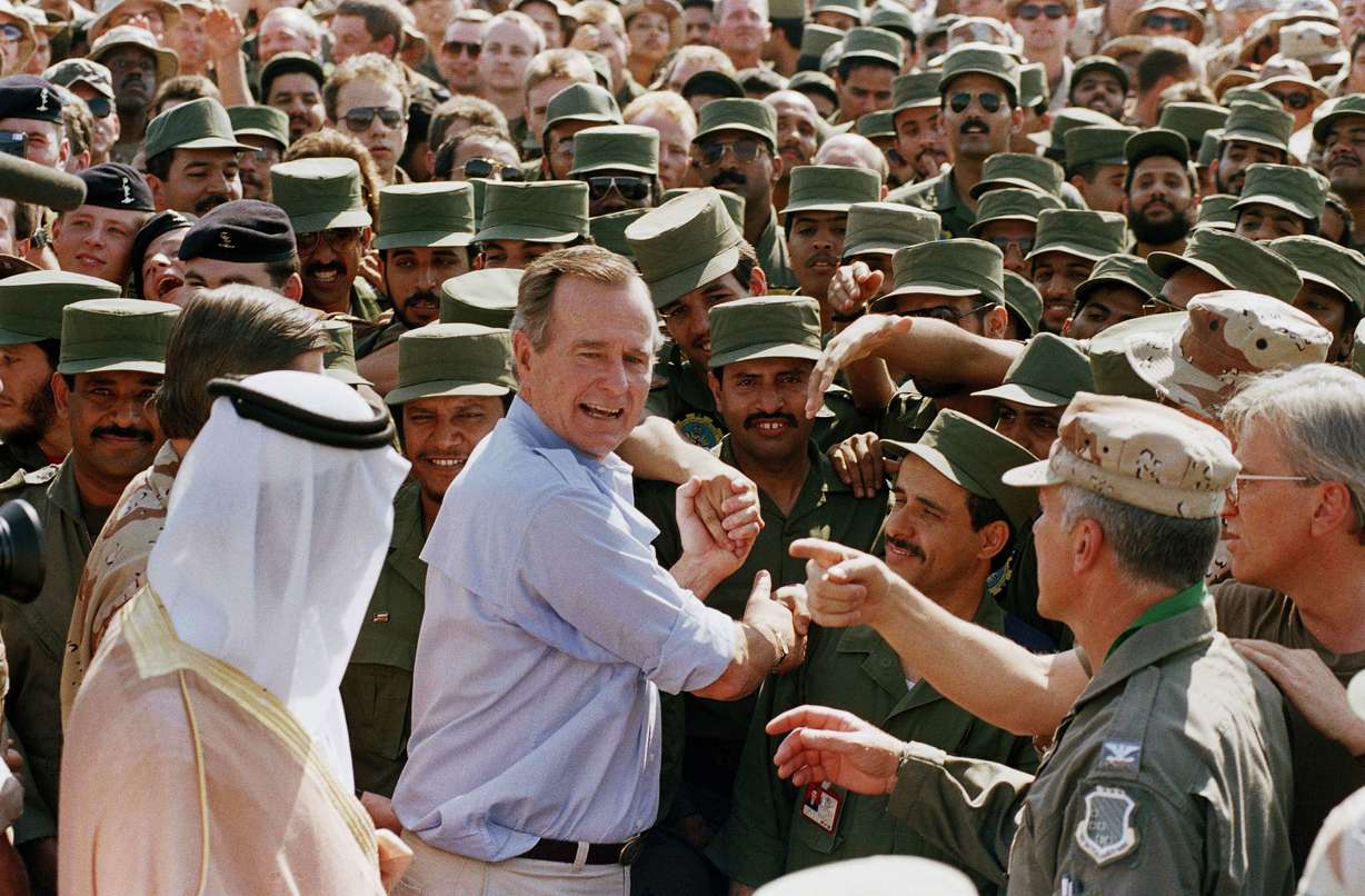FILE - In this Nov. 22, 1990 file photo, President George H.W. Bush is greeted by Saudi troops and others as he arrives in Dhahran, Saudi Arabia, for a Thanksgiving visit. (AP Photo/J. Scott Applewhite, File)