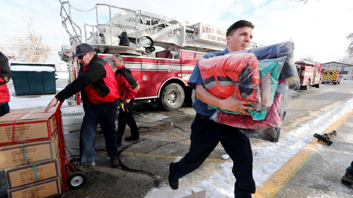 West Valley City firefighters carry boxes of coats they are donating to kids at Hillsdale Elementary School in West Valley City on Dec. 3, 2018. A coat drive for foster care youth will take place Saturday during the BYU-Utah game.