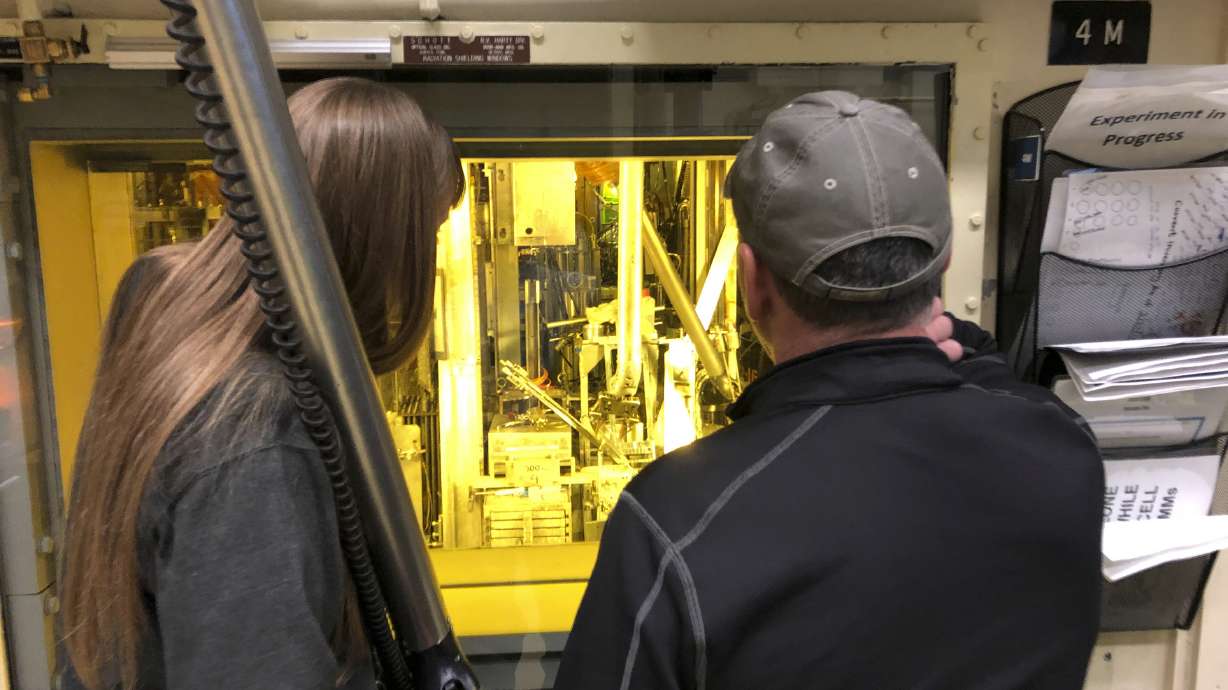 Hot cell operators Dawnette Hunter, left, and Scot White manipulate radioactive material from behind 4-foot-thick leaded glass at the Hot Fuel Examination Facility at the Idaho National Laboratory in 2018. A Utah energy cooperative says it will reduce the number of small modular nuclear reactors it will build in Idaho from 12 to six.