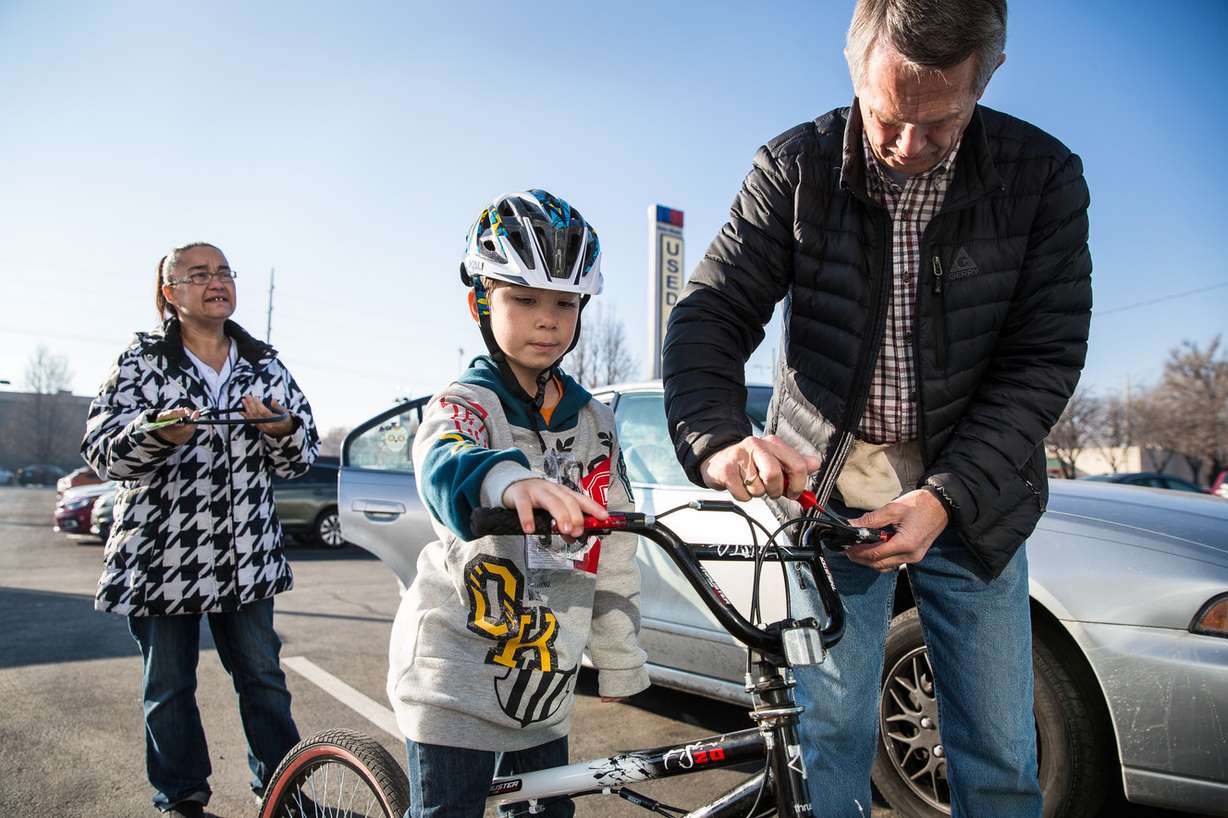 Richard Goddard, right, helps Aiden Lepak Lyons, 7, adjust the handbrake of his bike given by Free Bikes 4 Kidz at Nate Wade Subaru in Salt Lake City on Saturday, Dec. 15, 2018. (Photo: Qiling Wang, KSL)