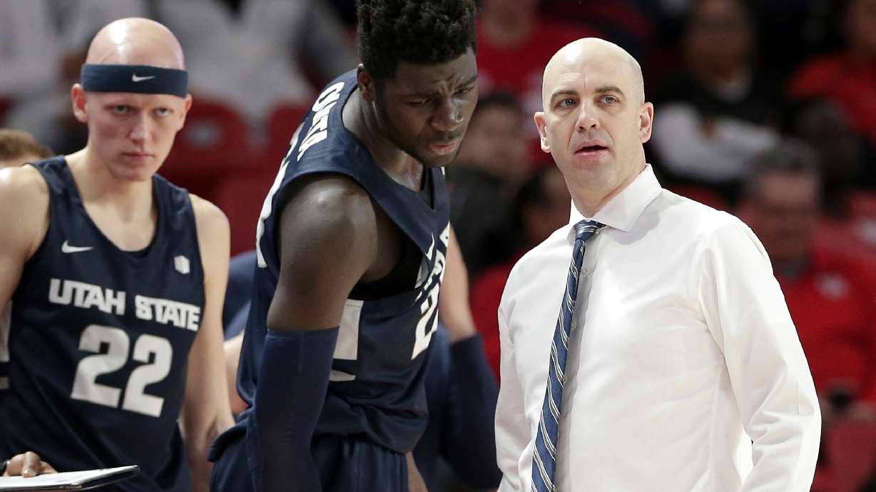 Utah State guard Brock Miller (22) looks on as center Neemias Queta, middle, talks with head coach Craig Smith during the first half of an NCAA college basketball game against Houston Thursday, Dec. 20, 2018, in Houston. (AP Photo/Michael Wyke)