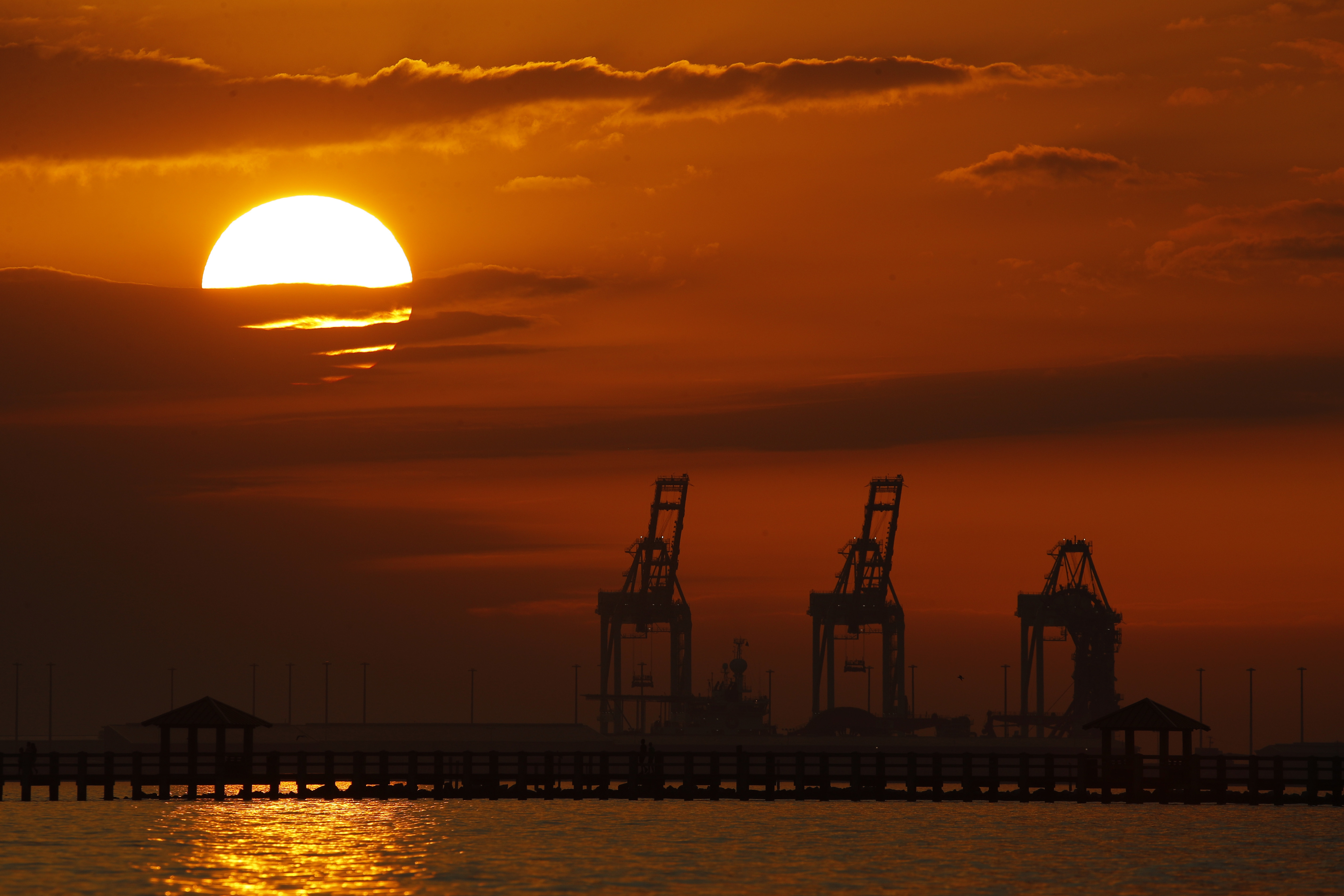 In this Dec. 2, 2018, file photo cranes at the Port of Gulfport are silhouetted by the setting sun at Gulfport, Miss. The Trump administration and China are facing growing pressure to blink in their six-month stare-down over trade because of jittery markets and portents of economic weakness. The longer their trade war lasts, the longer companies and consumers will feel the pain of higher-priced imports and exports. (AP Photo/Charlie Riedel, File)