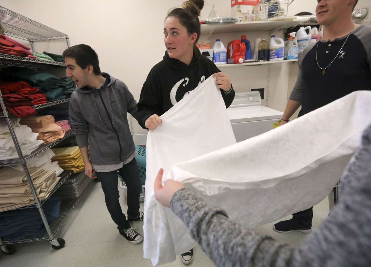 Juan Diego High School seniors Nikolas Santiago and Grace Anglesey look into the other room as they fold tablecloths while volunteering at the Sandy Senior Citizens Center in Sandy on Wednesday, Jan. 9, 2019. Photo: Kristin Murphy, KSL