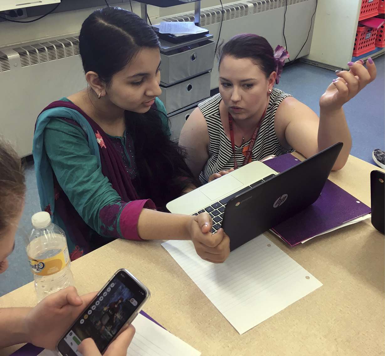 In this May 23, 2018 photo, teacher Gianna Gurga, right, talks with student Maisha Chowdhury Jabia in a class on financial literacy at Dag Hammarskjold Middle School in Wallingford, Conn. To guide student lessons and behavior Gurga uses the Classcraft, one of many programs that borrow elements from video games to engage students. Games have been a part of education for generations, but not new technology is powering programs that borrow elements from video games to engage students, customize learning and modify behaviors. (AP Photo/Michael Melia)