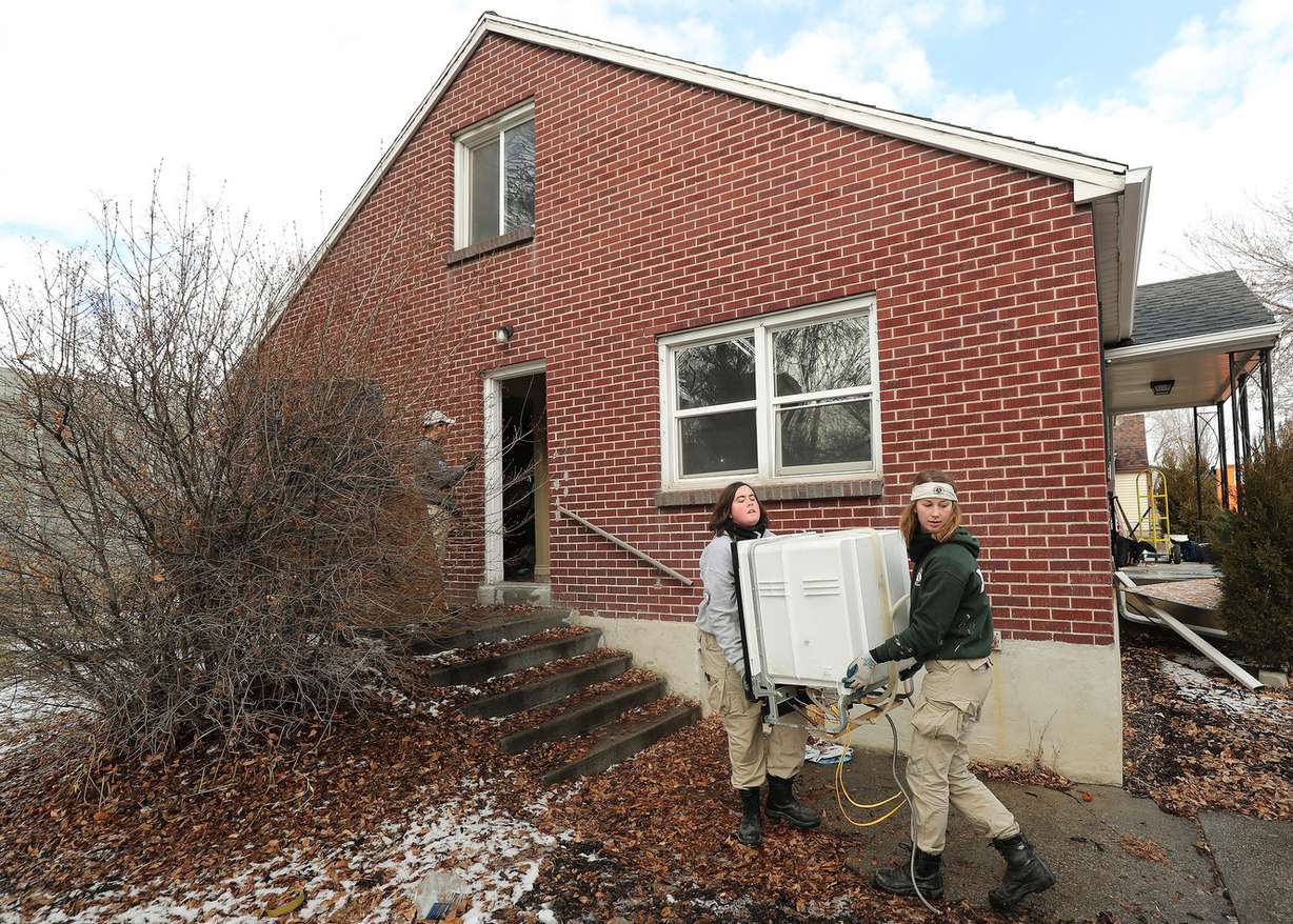 AmeriCorps volunteers Alex Elliott and Meghan Schwob remove an item from a Midvale home owned by the Utah Department of Transportation on Wednesday, Jan. 16, 2019. (Photo: Jeffrey D. Allred, KSL)