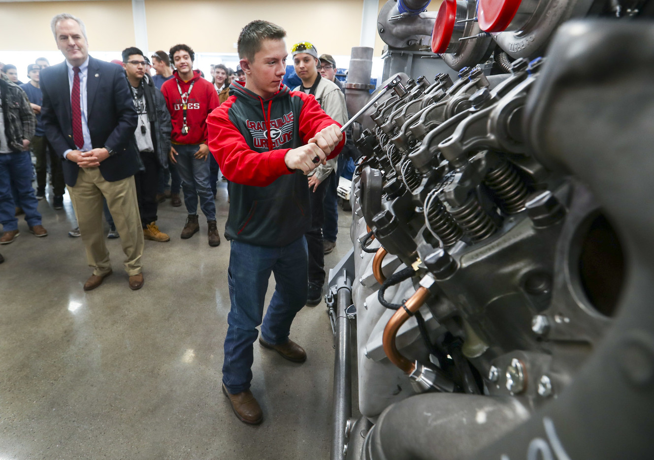 Val Hale, executive director of the Utah Governor’s Office of Economic Development, left, watches as Grantsville High School senior Seth Hicken tightens a rocker arm on a Detroit Diesel series 4000 V16 diesel engine at Detroit Diesel in Tooele on Wednesday, Jan. 23, 2019. (Photo: Steve Griffin, KSL)