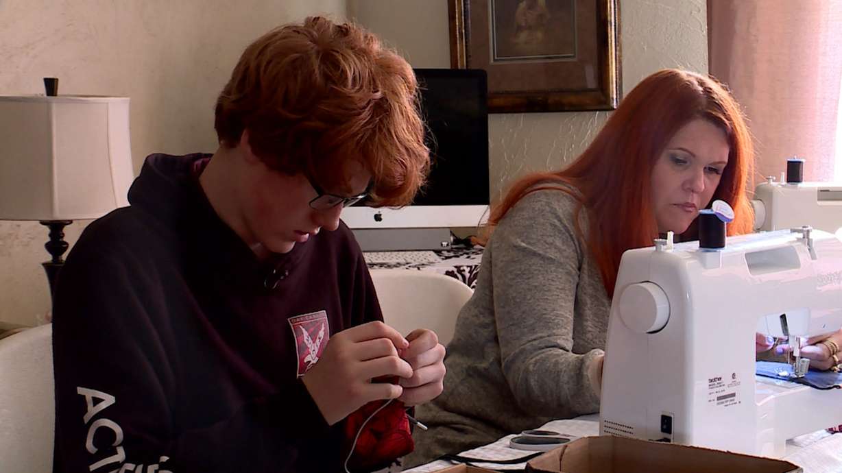Logan Merrill sits next to his mother Tori Merrill as she sews "Just Don't" bags. (Photo: KSL TV)