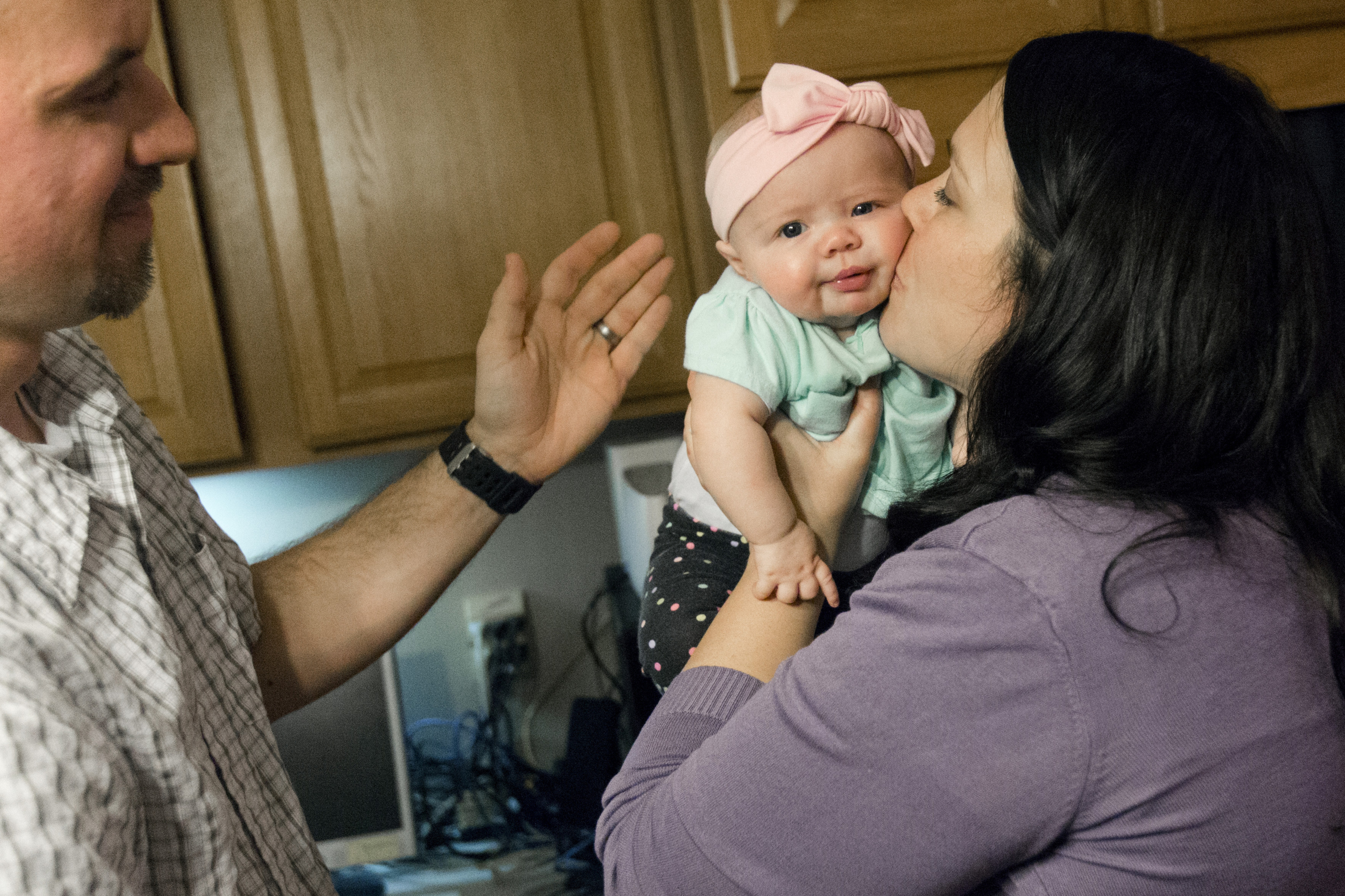 Erica Goulding kisses her youngest child, Emery, 3-month- old, after being handed to her mother by her father, Devin, in their home on Monday, Feb. 11, 2019, in Orem, Utah. (Evan Cobb/The Daily Herald via AP)