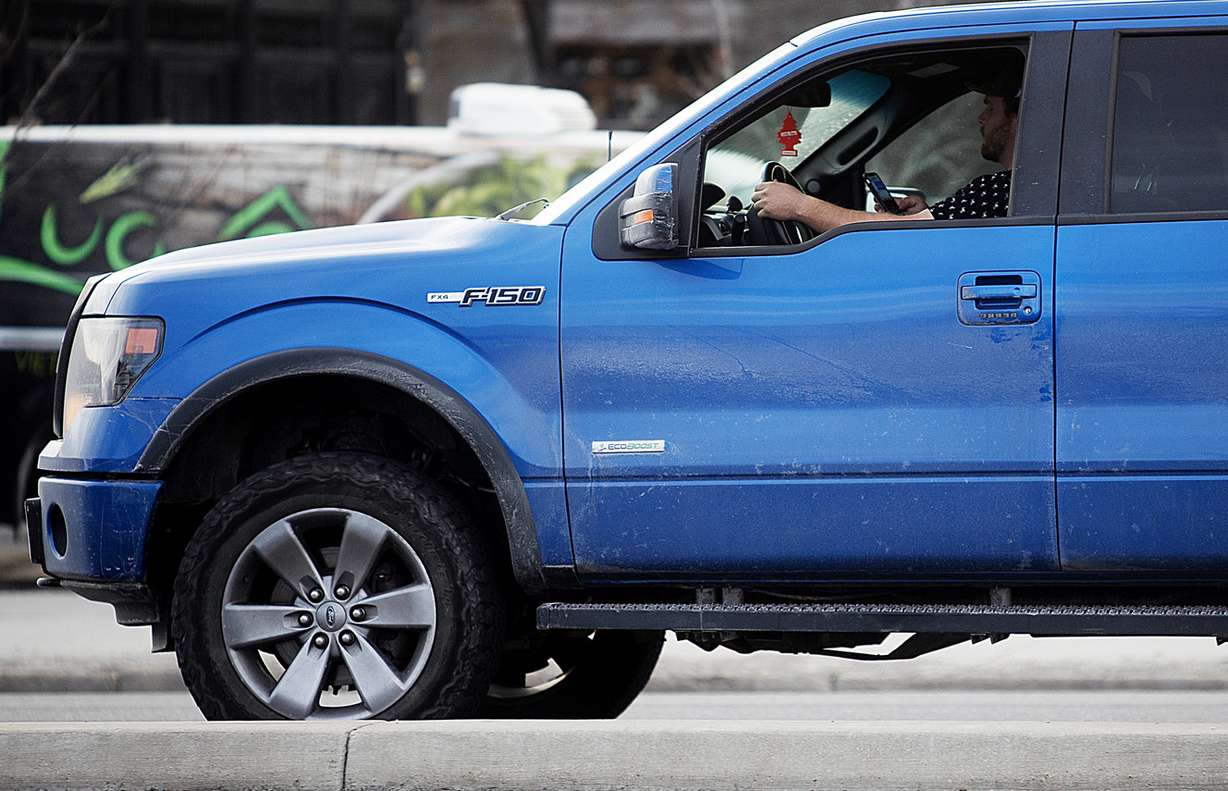 A driver holds his cellphone up as he drives on State Street in Salt Lake City on Monday, Feb. 25, 2019. (Photo: Scott G Winterton, KSL)