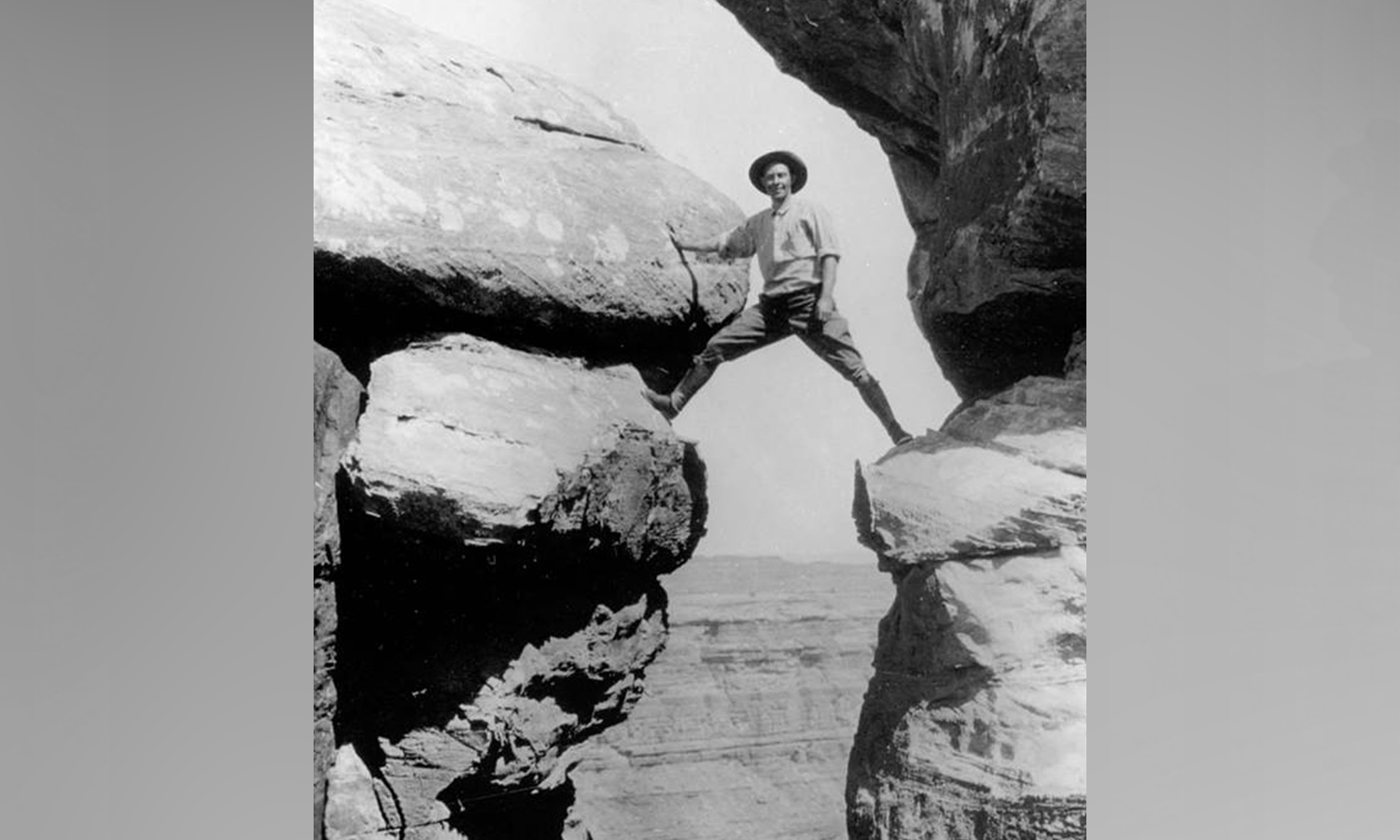 Photographer Emery Kolb straddling boulder cliffs above Stillwater Canyon in 1911. (Photo: National Park Service)